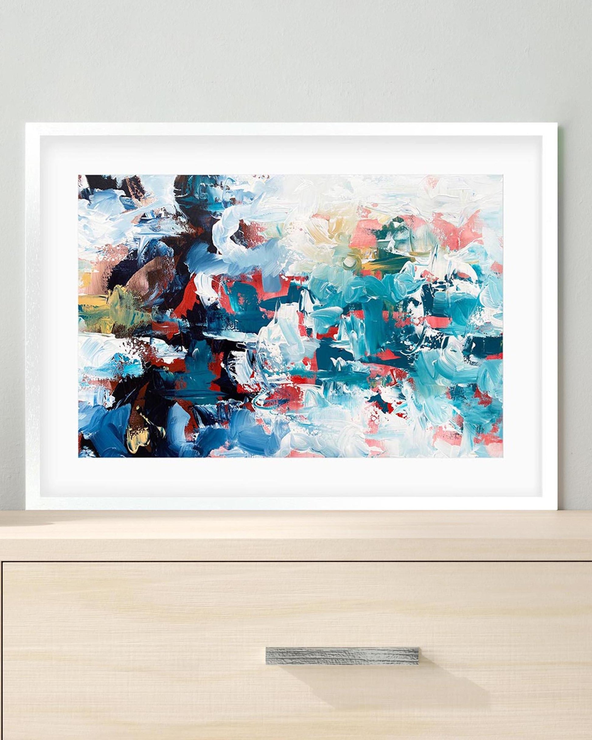 Framed abstract painting with colorful brushstrokes on a light gray wall.