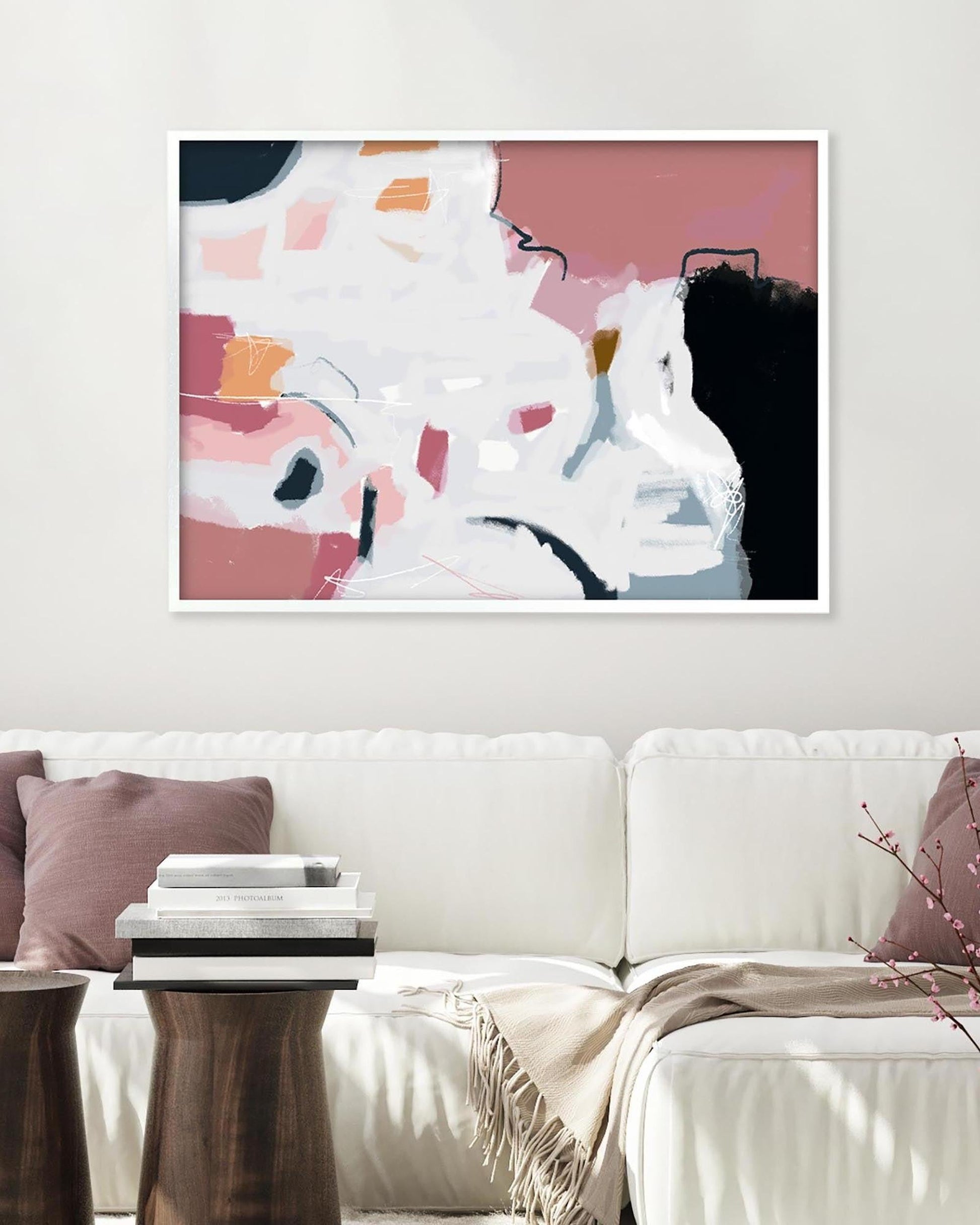 Abstract art print on a wall above a white sofa in a living room.
