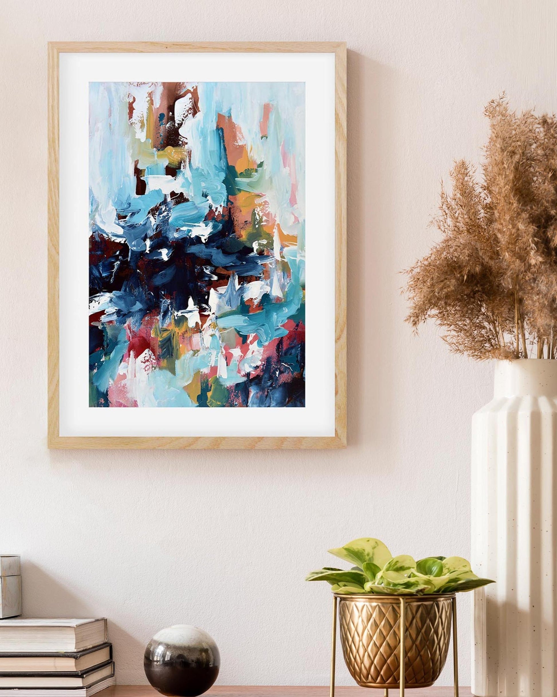 Framed abstract painting on a wall with decorative vases and plants.