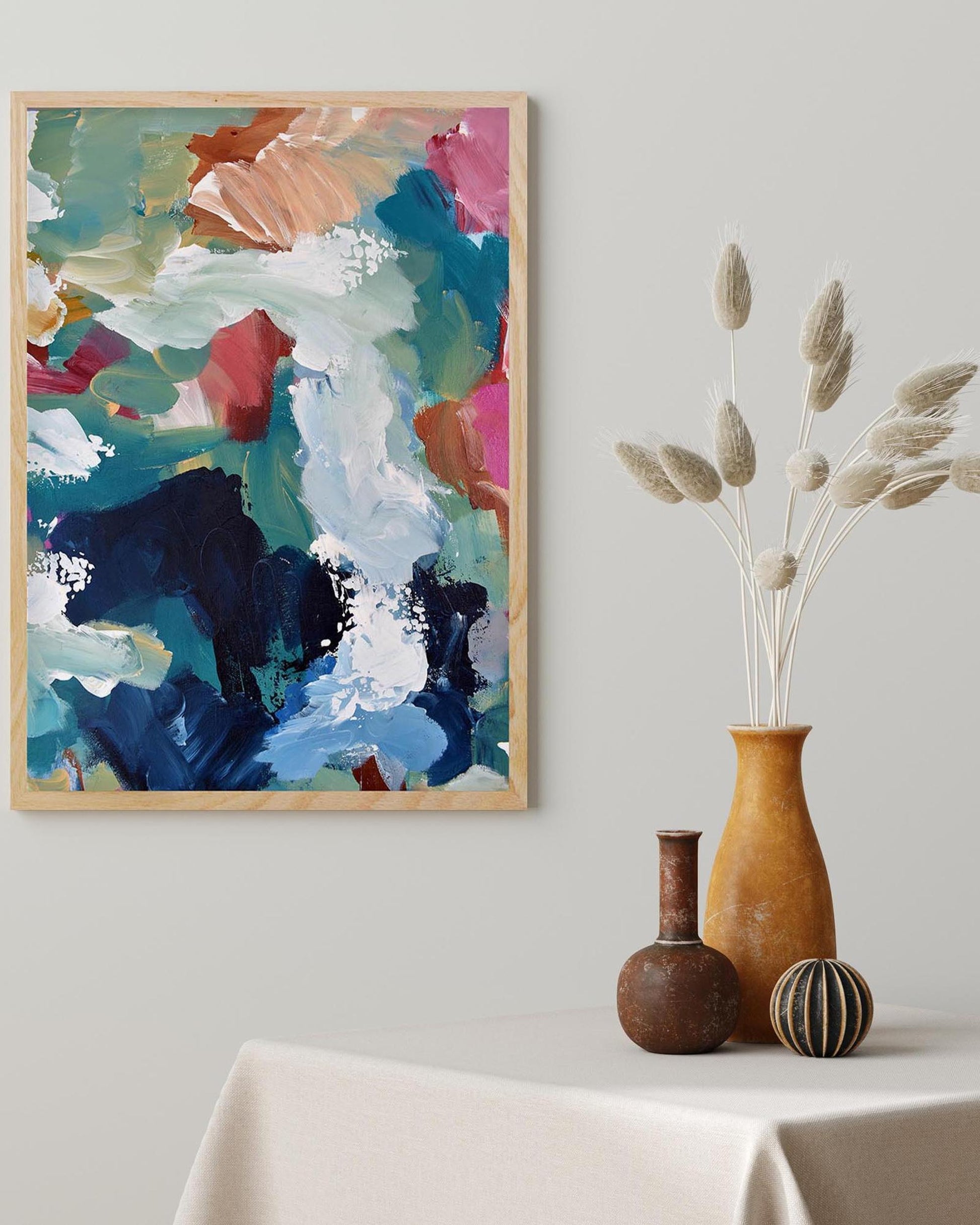 Colorful abstract painting on a wall with decorative vases on a table below.