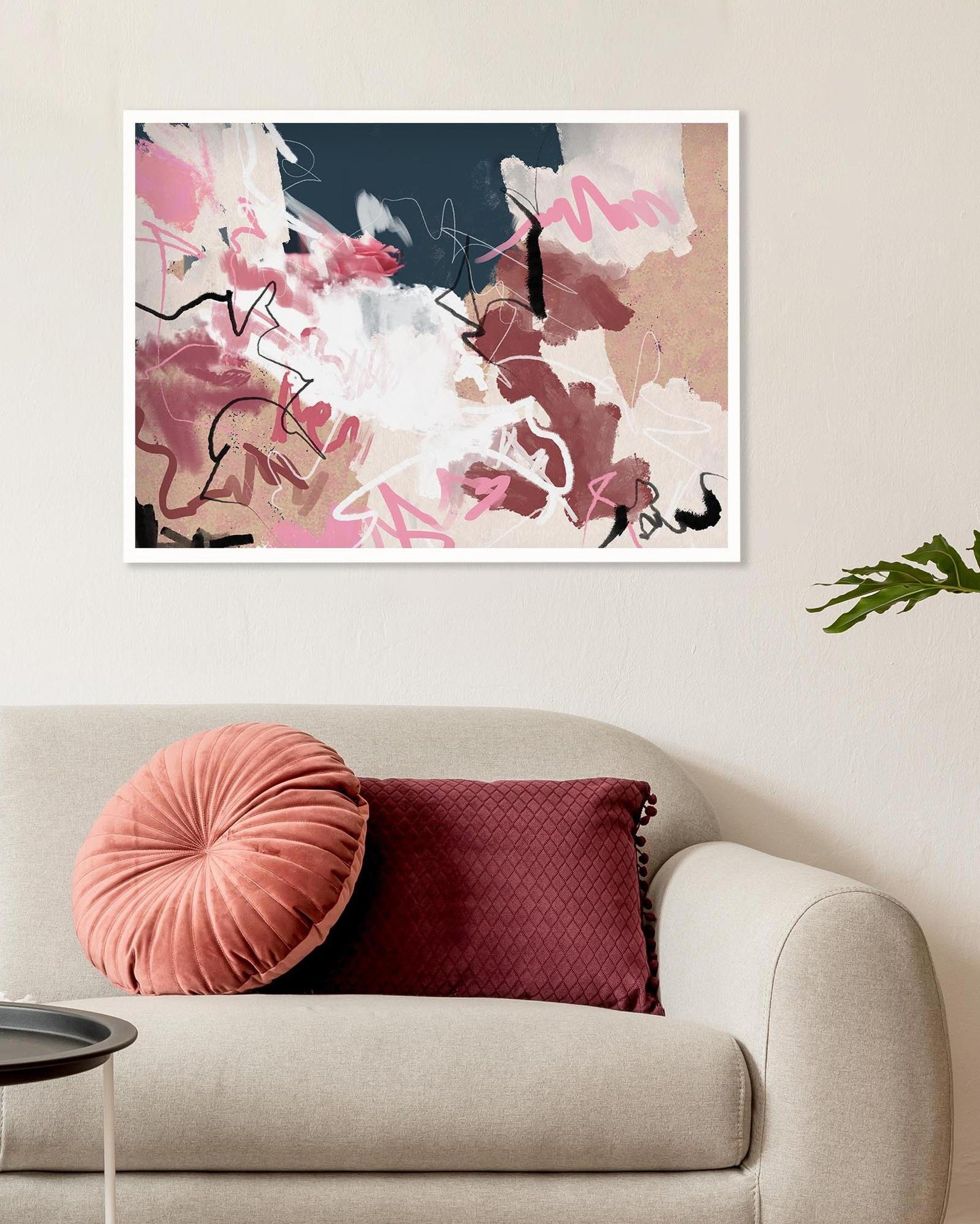 Abstract art print on a wall above a sofa with decorative pillows.