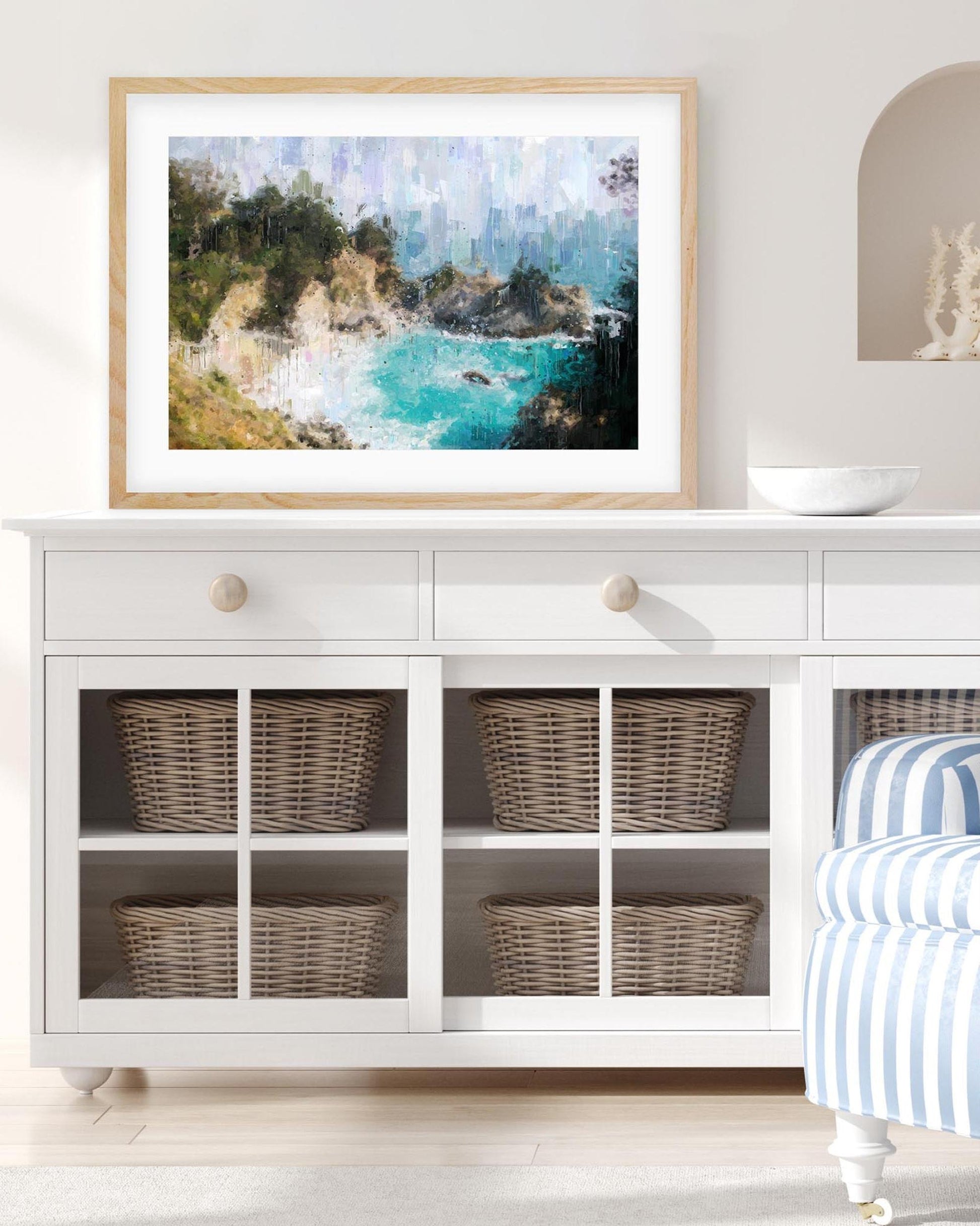 Framed artwork above a white cabinet with wicker baskets.