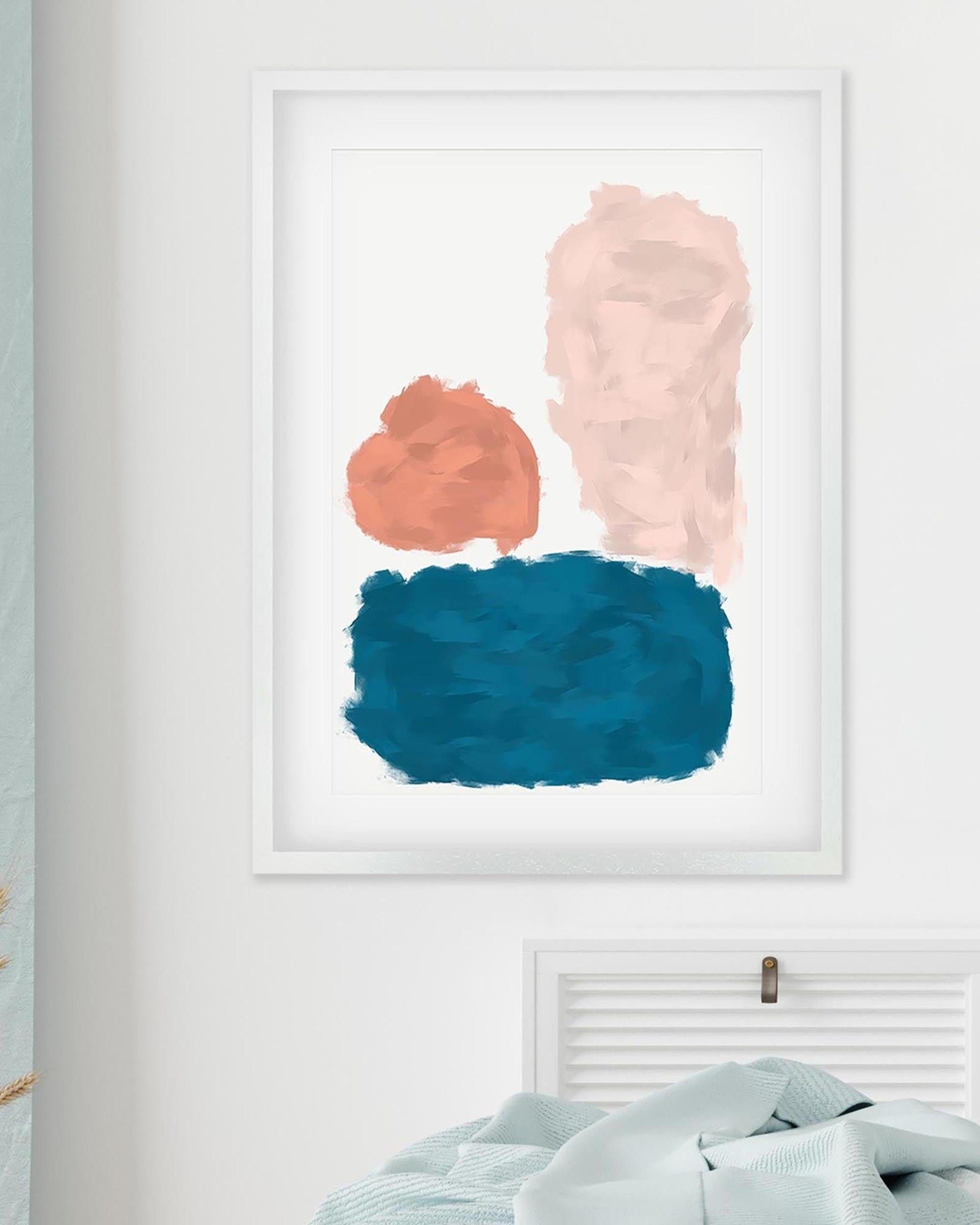 Framed abstract art with pink, orange, and blue brush strokes on a white wall.