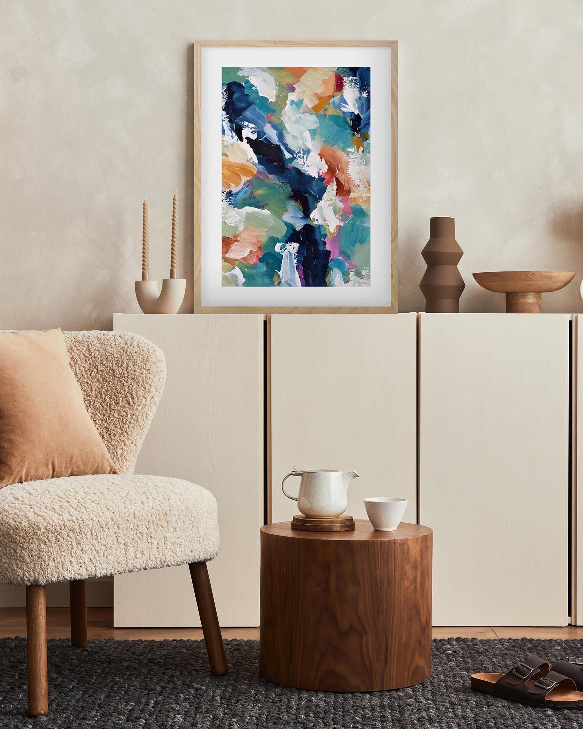 Modern living room with a colorful abstract painting, wooden side table, and armchair.