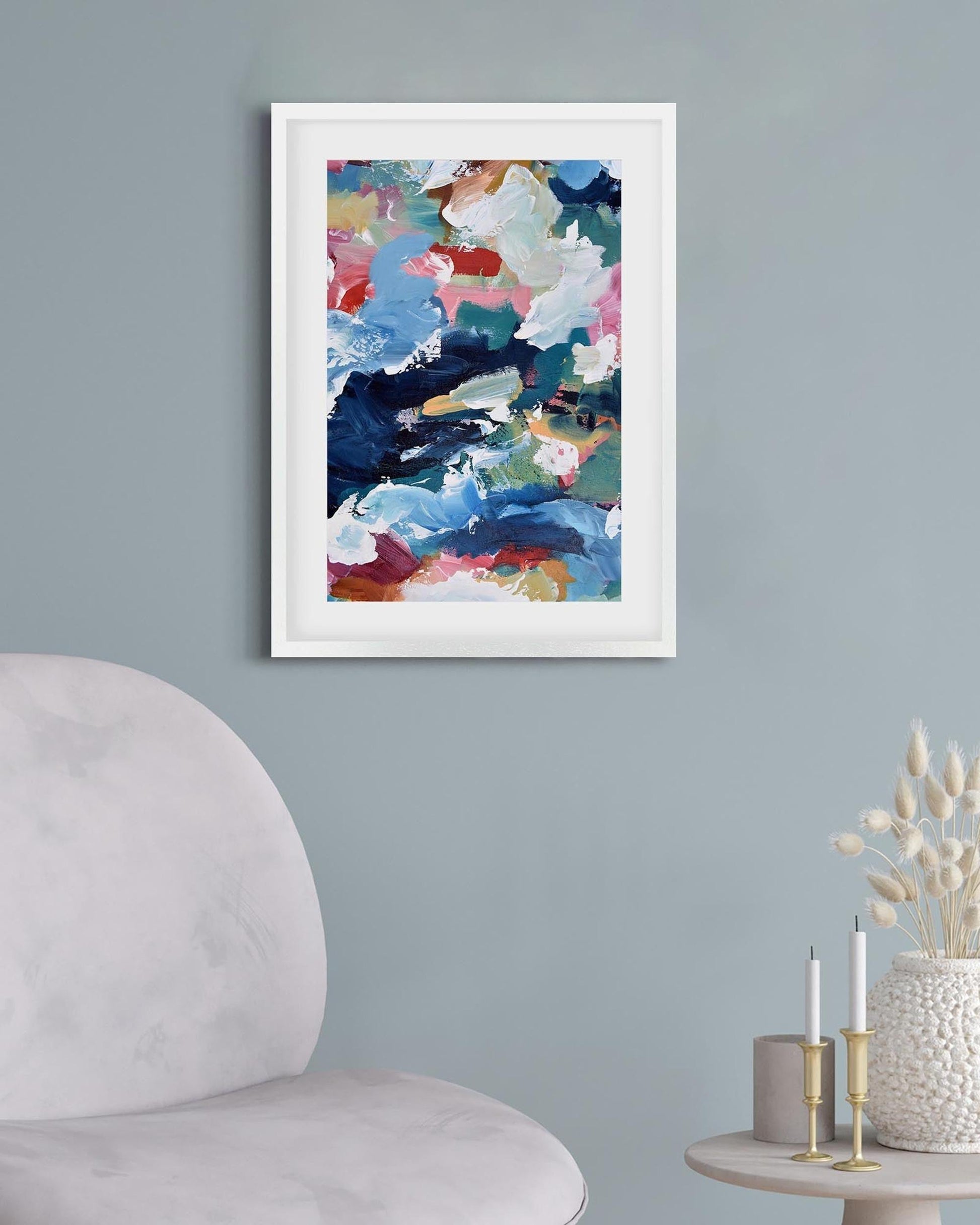 Colorful abstract art print on a gray wall above a white chair.