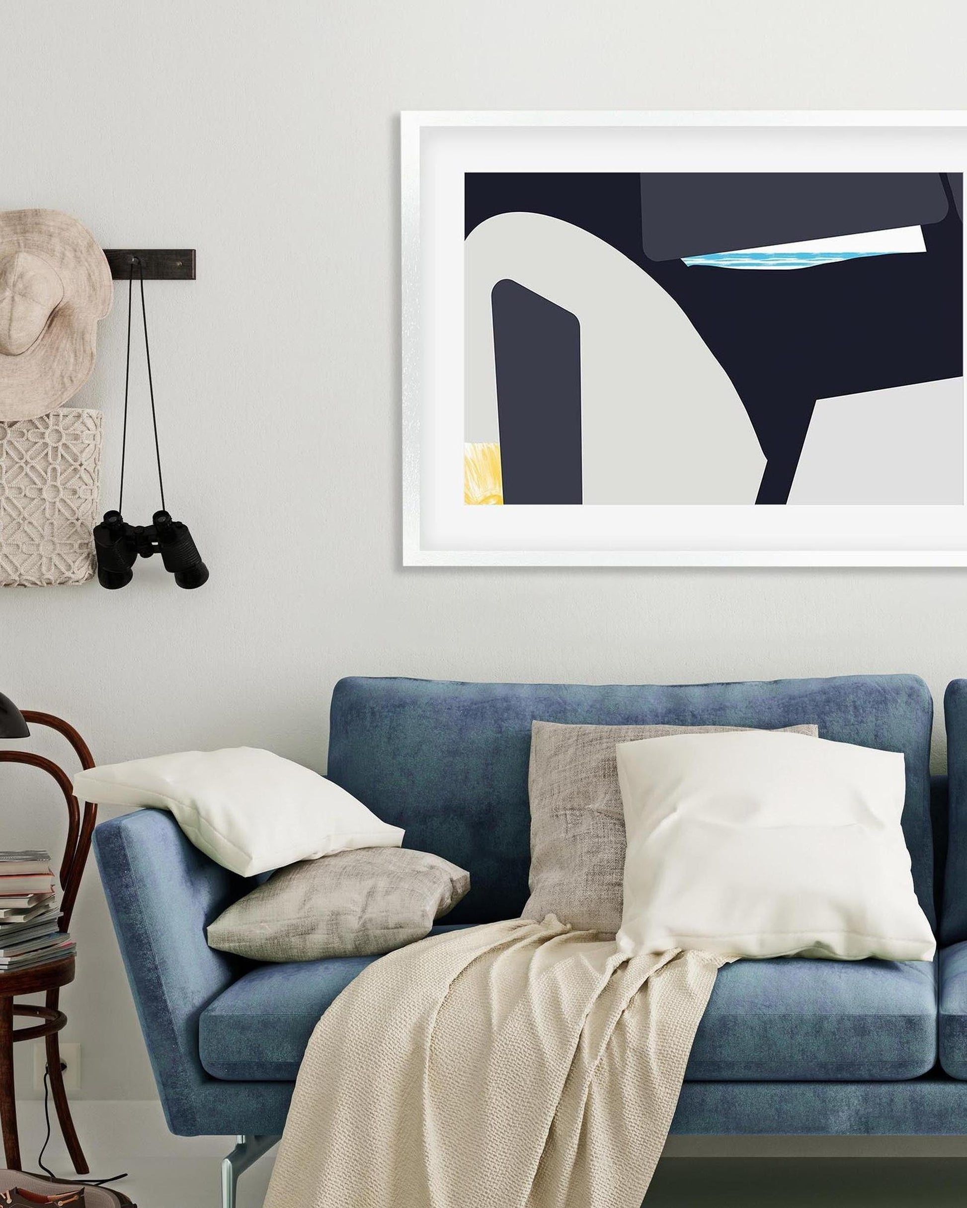 Living room with a blue sofa, framed abstract art, and decorative items.