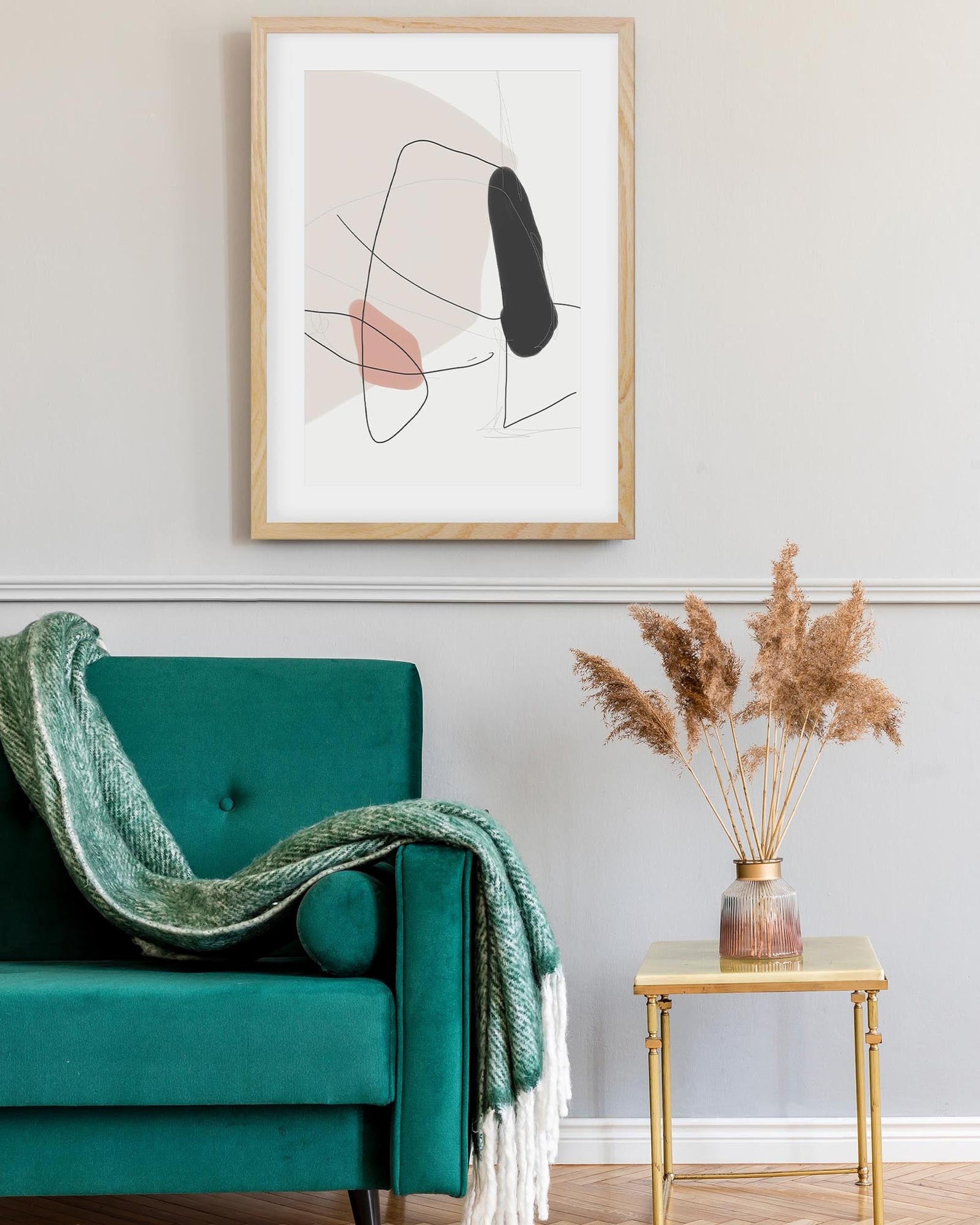 Teal armchair with a green blanket, abstract art on the wall, and a small table with dried plants.