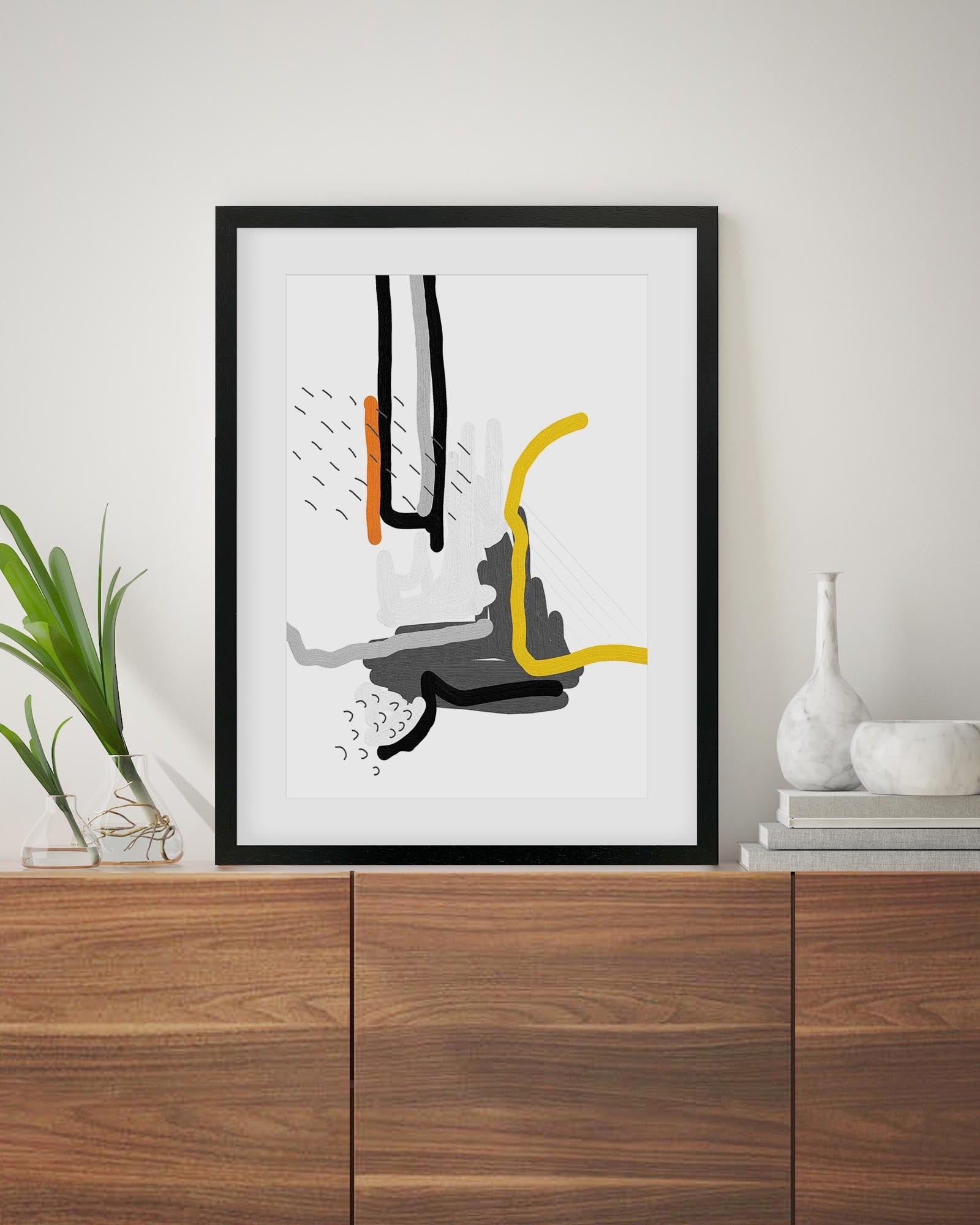 Abstract art print in a black frame on a wooden surface with decorative items.