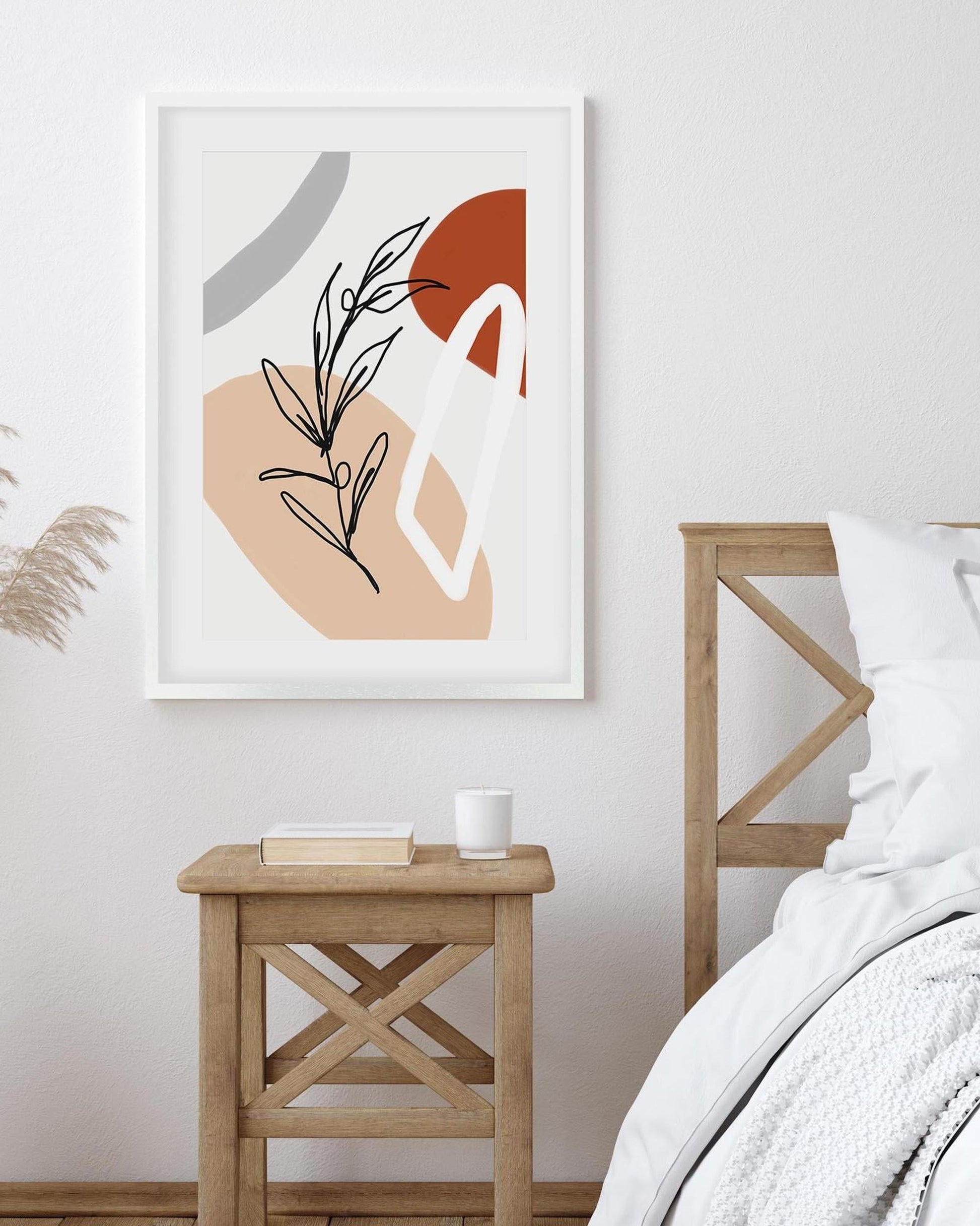 Abstract art print on a wall above a wooden side table in a bedroom.