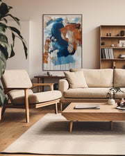 Modern living room with beige sofa, armchair, and abstract art on the wall.