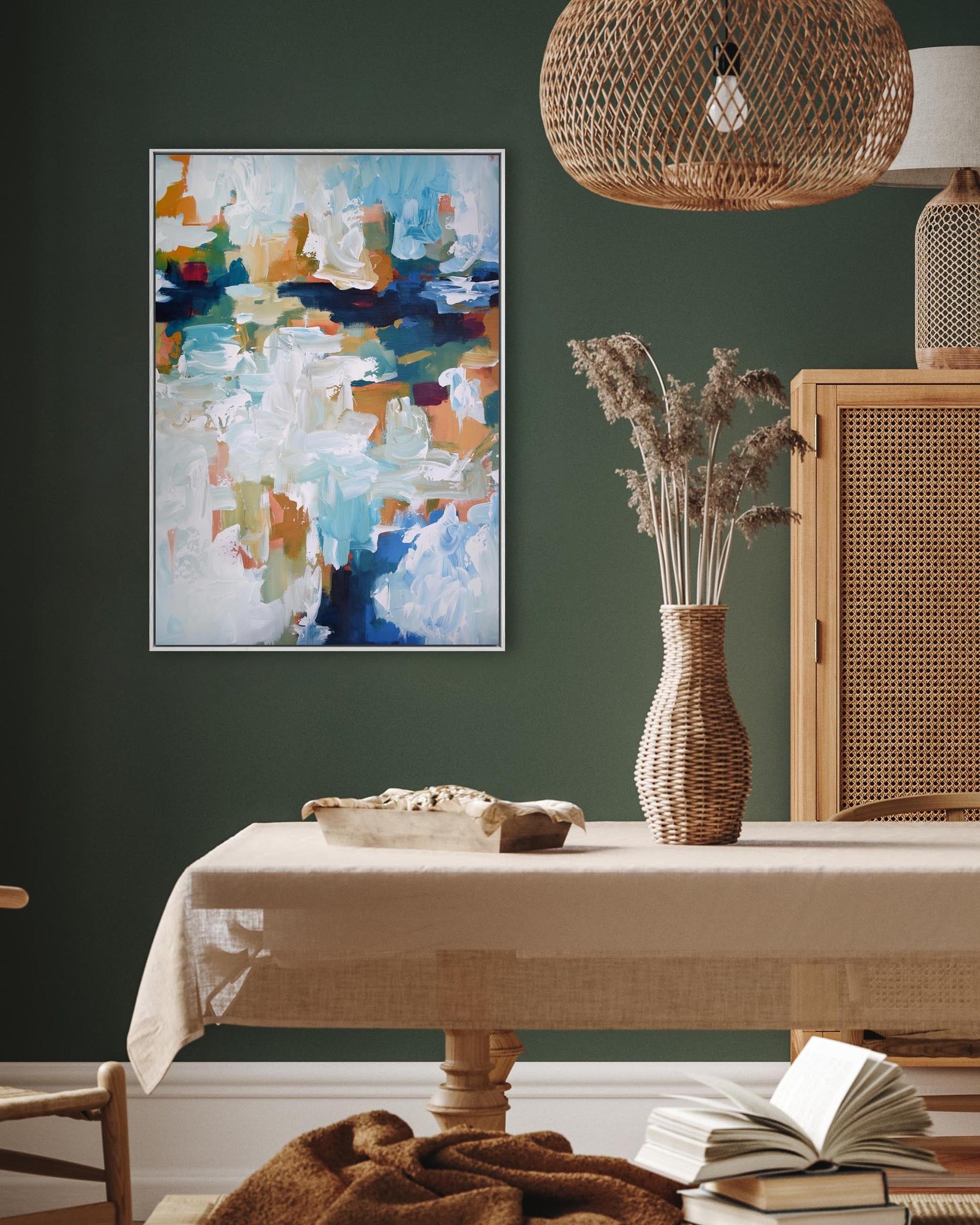 Dining room with a table, abstract painting, and decorative items against a green wall.