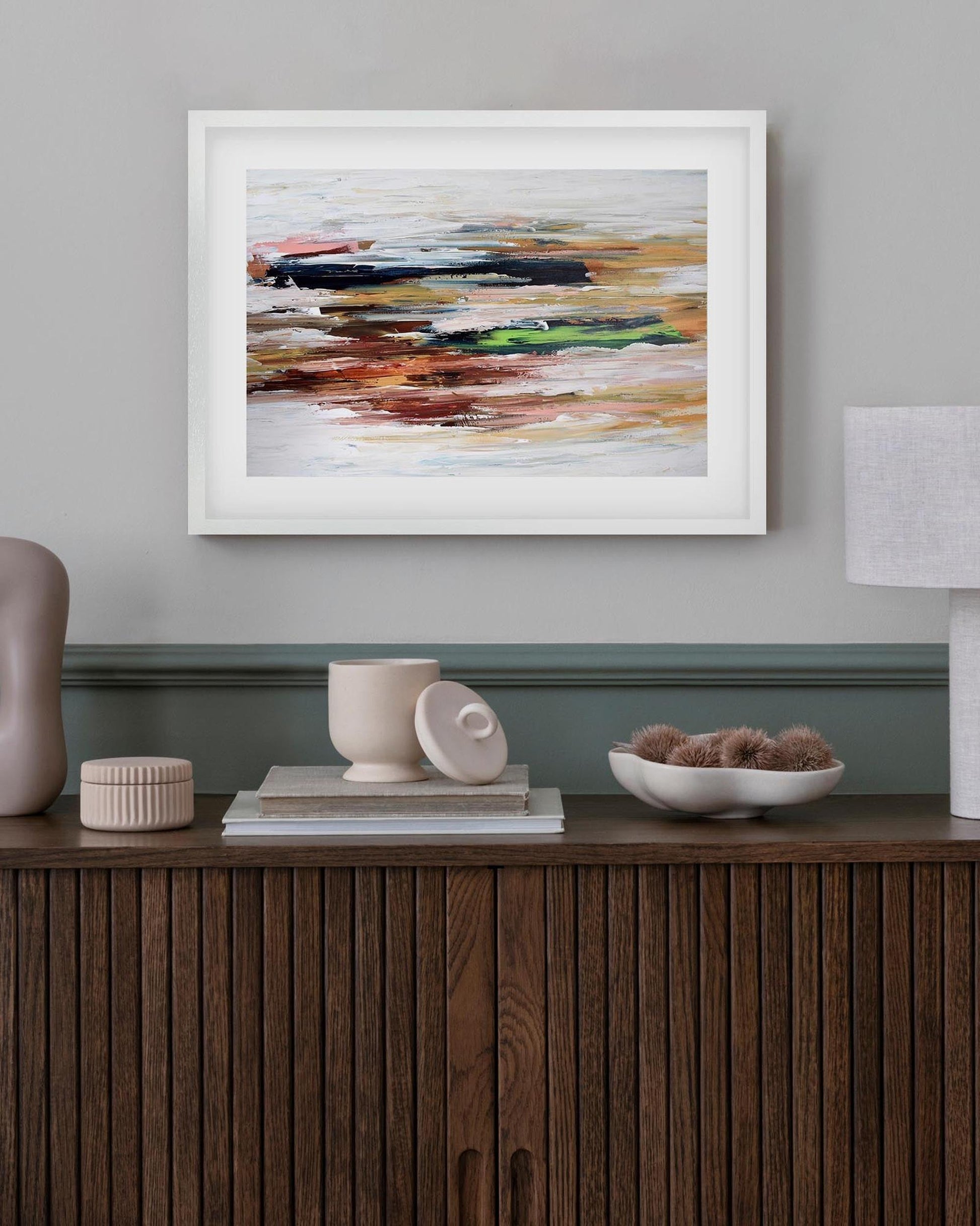 Framed abstract painting on a wall above a wooden console table with decorative items.