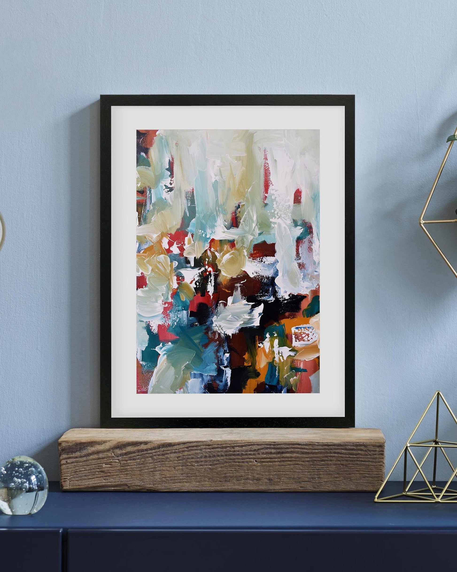 Framed abstract art piece on a blue wall with decorative elements.