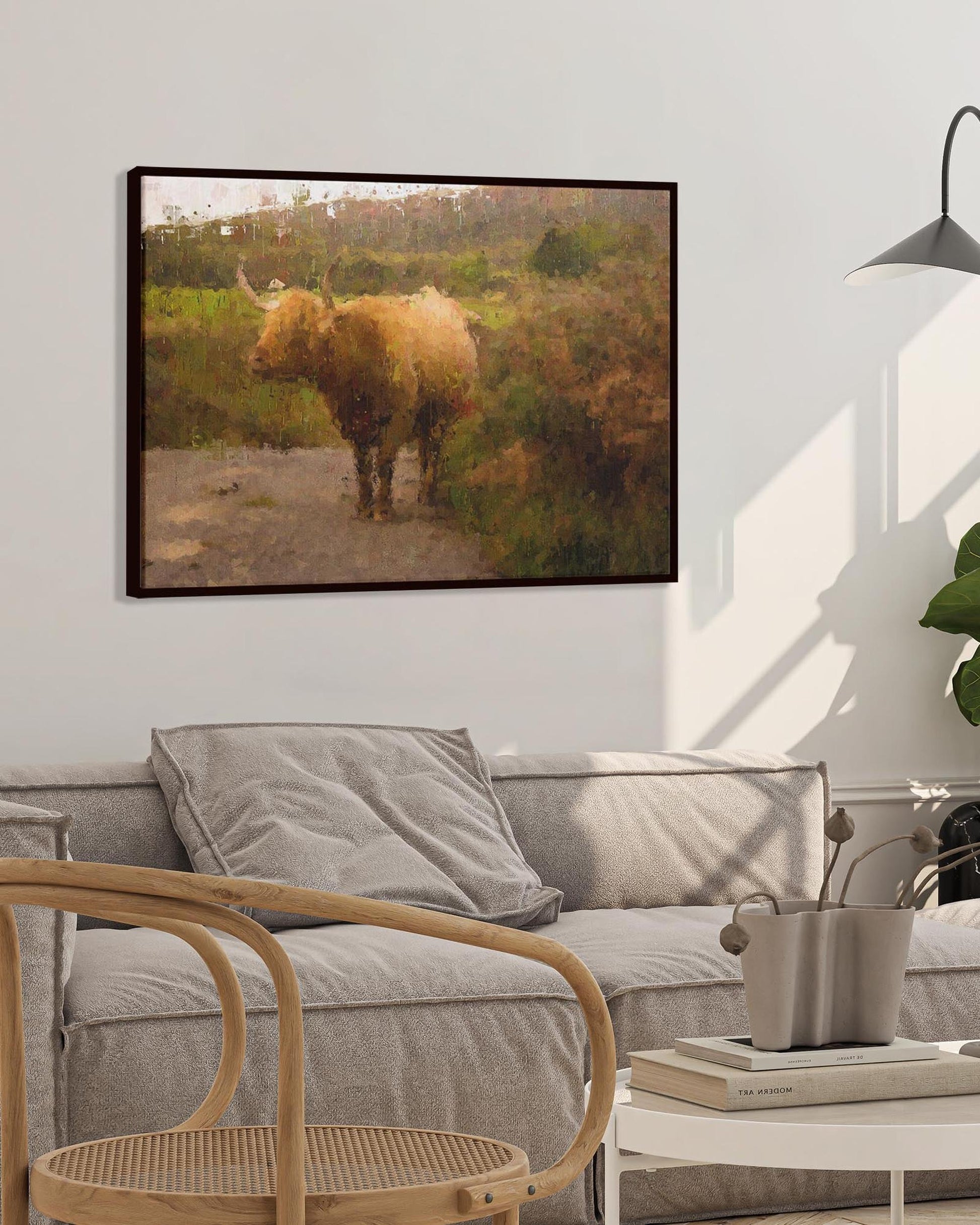 Living room with a gray sofa, wooden chair, and framed picture of a Highland cow on the wall.