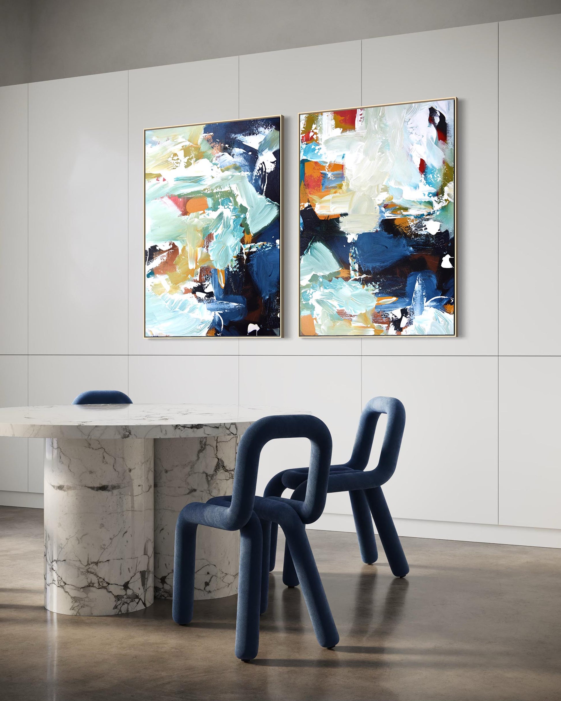 Two abstract paintings on a wall above a modern dining table and chairs.