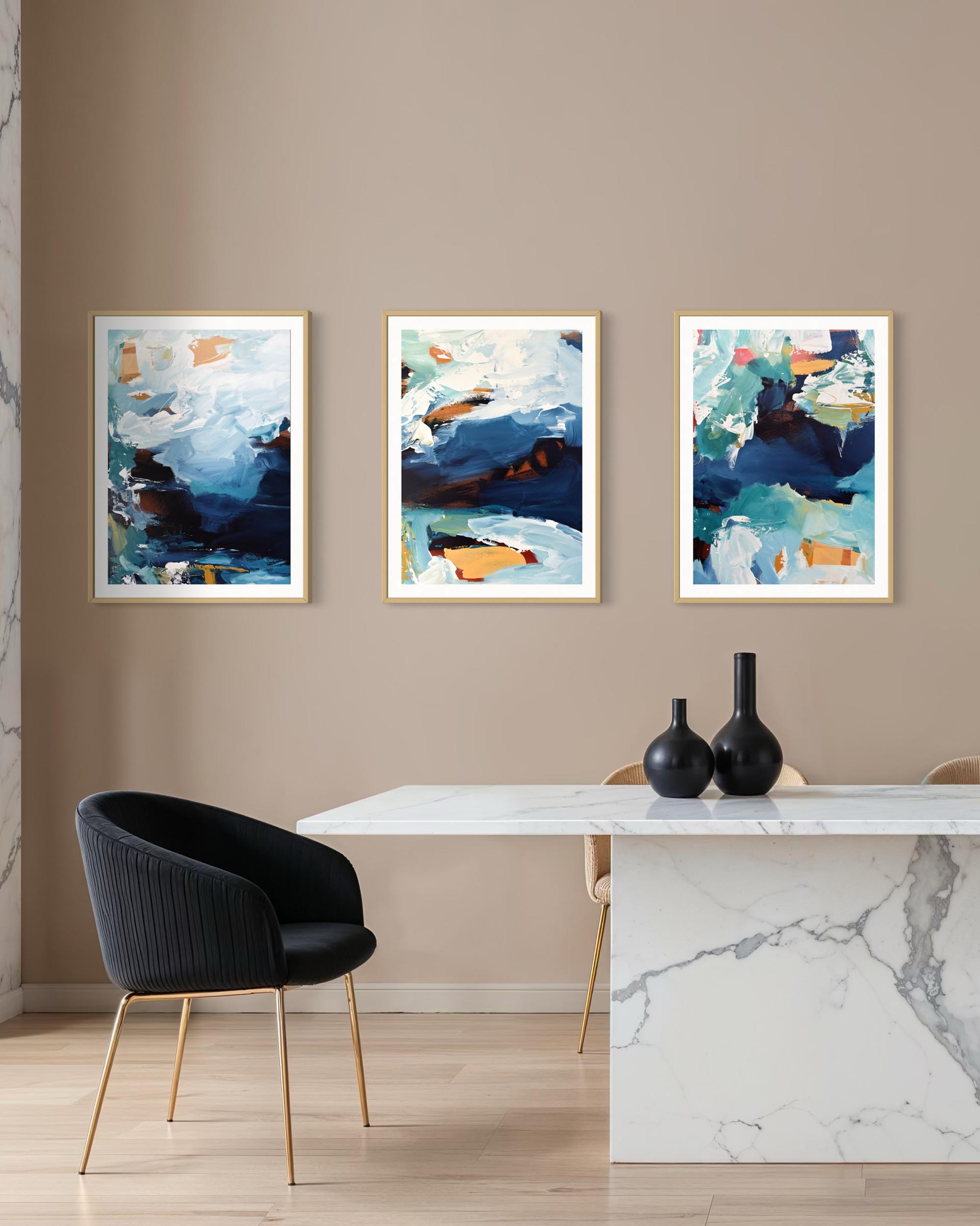 Three abstract paintings on a wall above a dining table with vases.