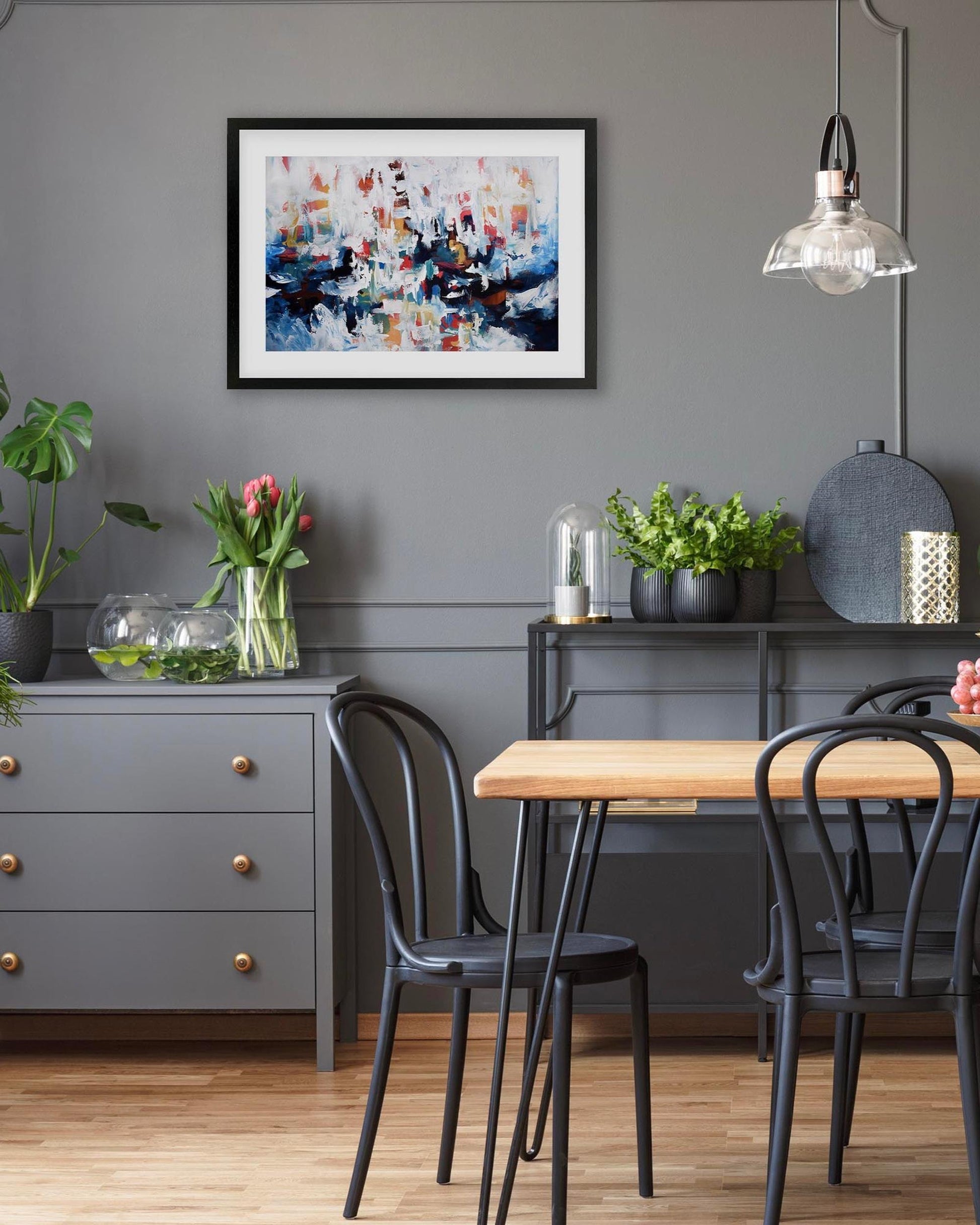 Dining room with a wooden table, black chairs, and a gray wall with abstract art.