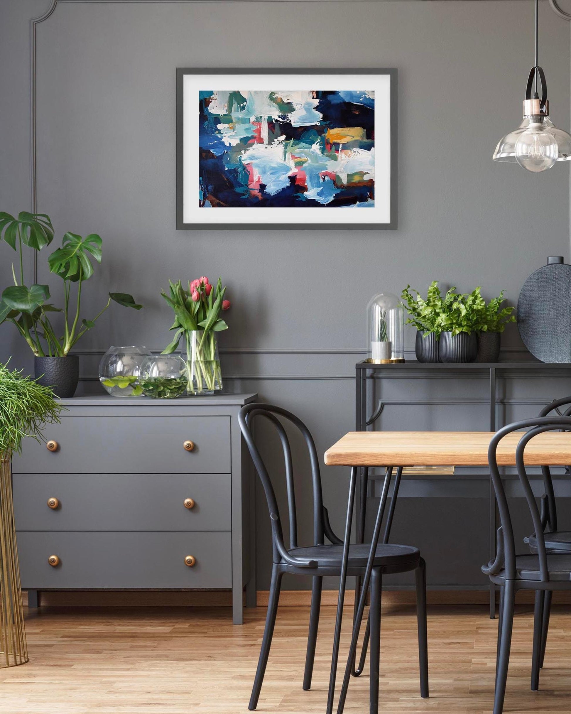 Dining room with a gray wall, wooden table, black chairs, and decorative elements.