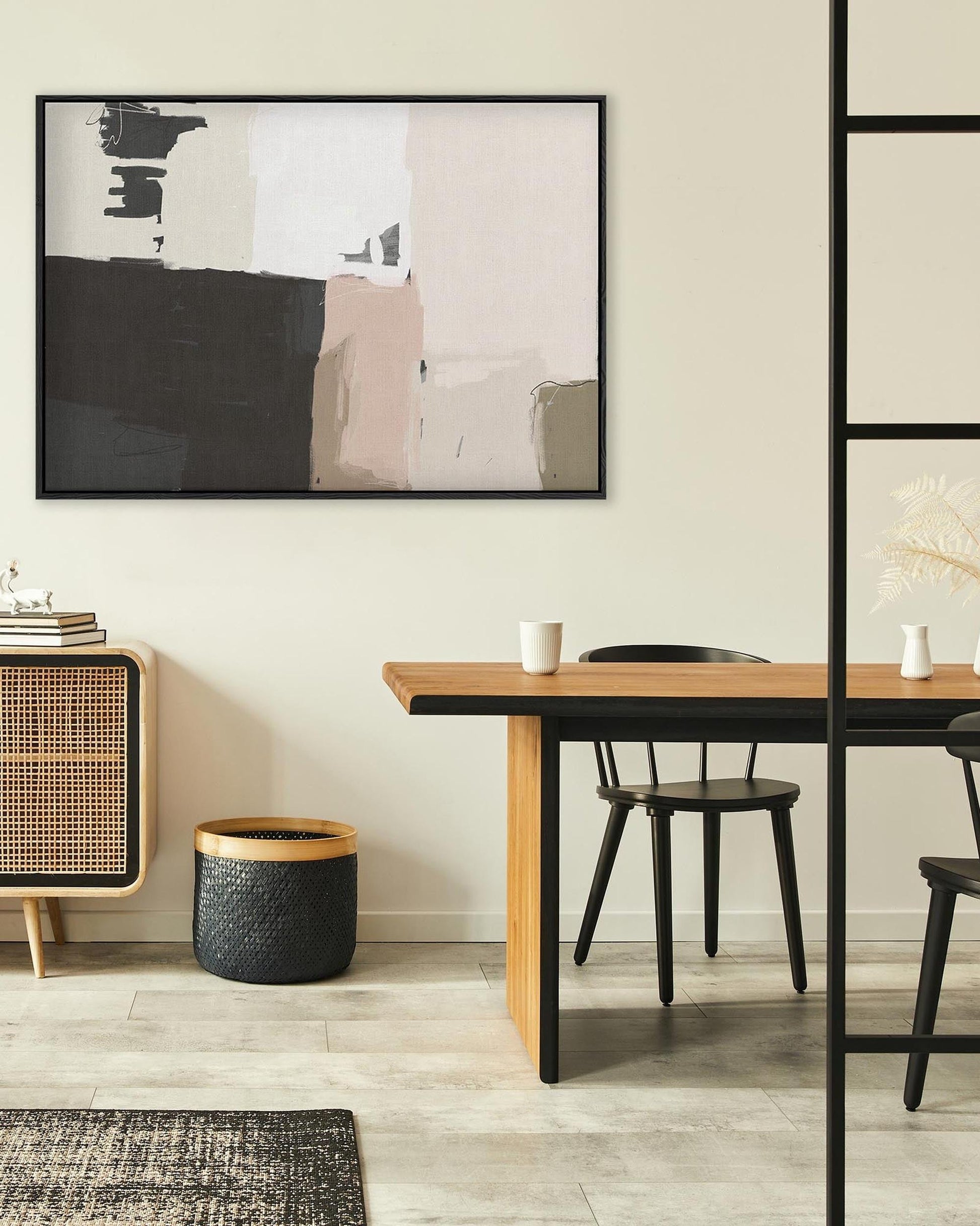 Modern dining room with a wooden table, black chairs, and a framed abstract art piece on the wall.