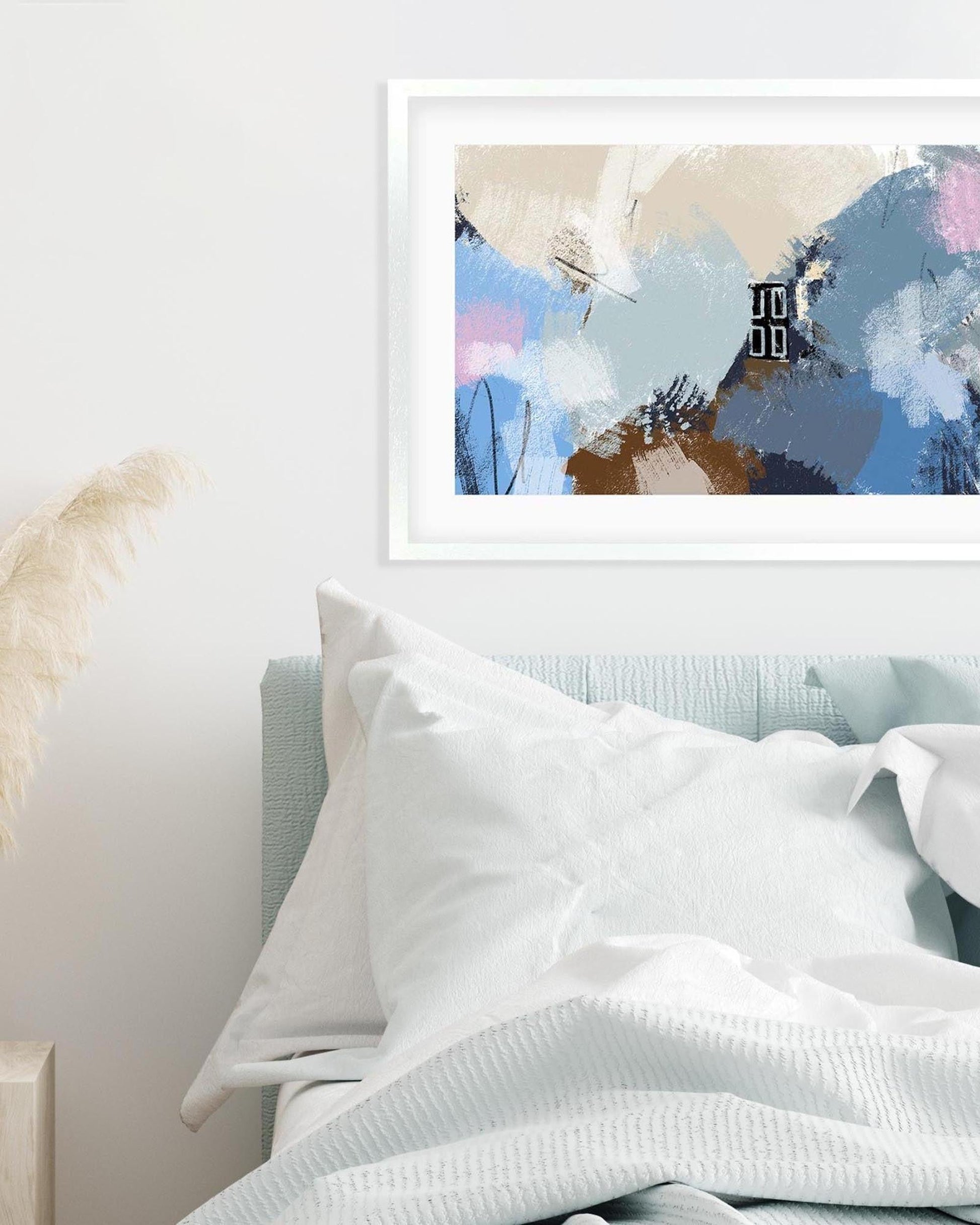 Abstract art print on a wall above a bed with white bedding