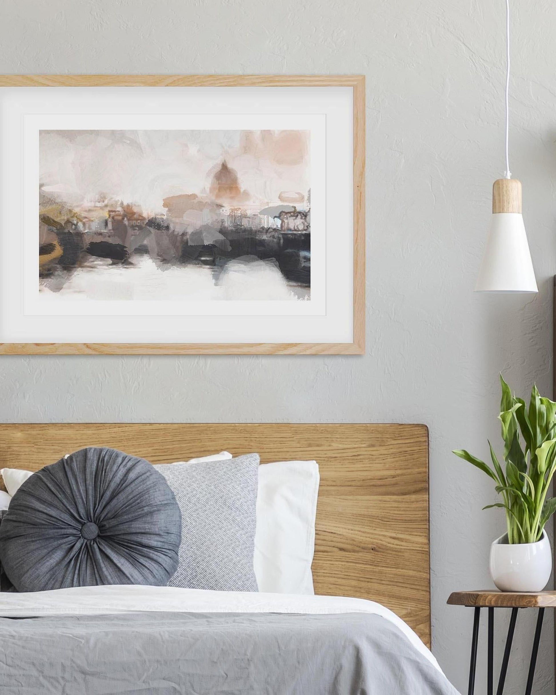 Bedroom interior with wooden headboard, gray and white pillows, framed abstract art, and a plant.