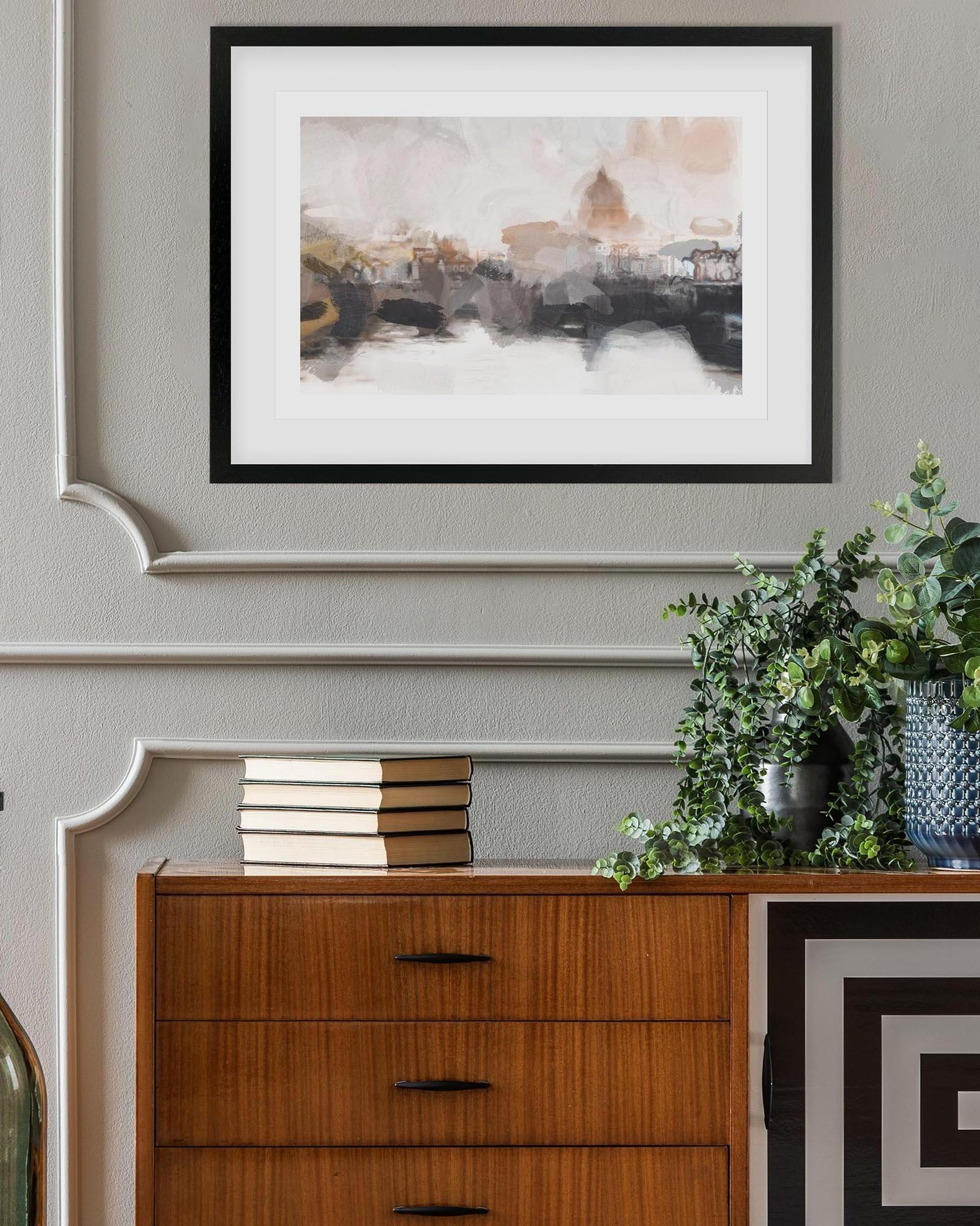 Framed abstract art above a wooden dresser with decorative items.