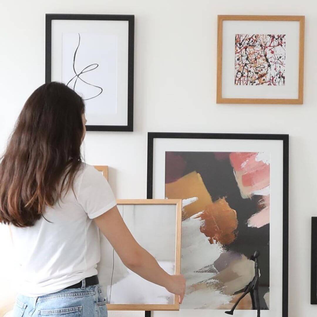 woman holding framed artwork in living room