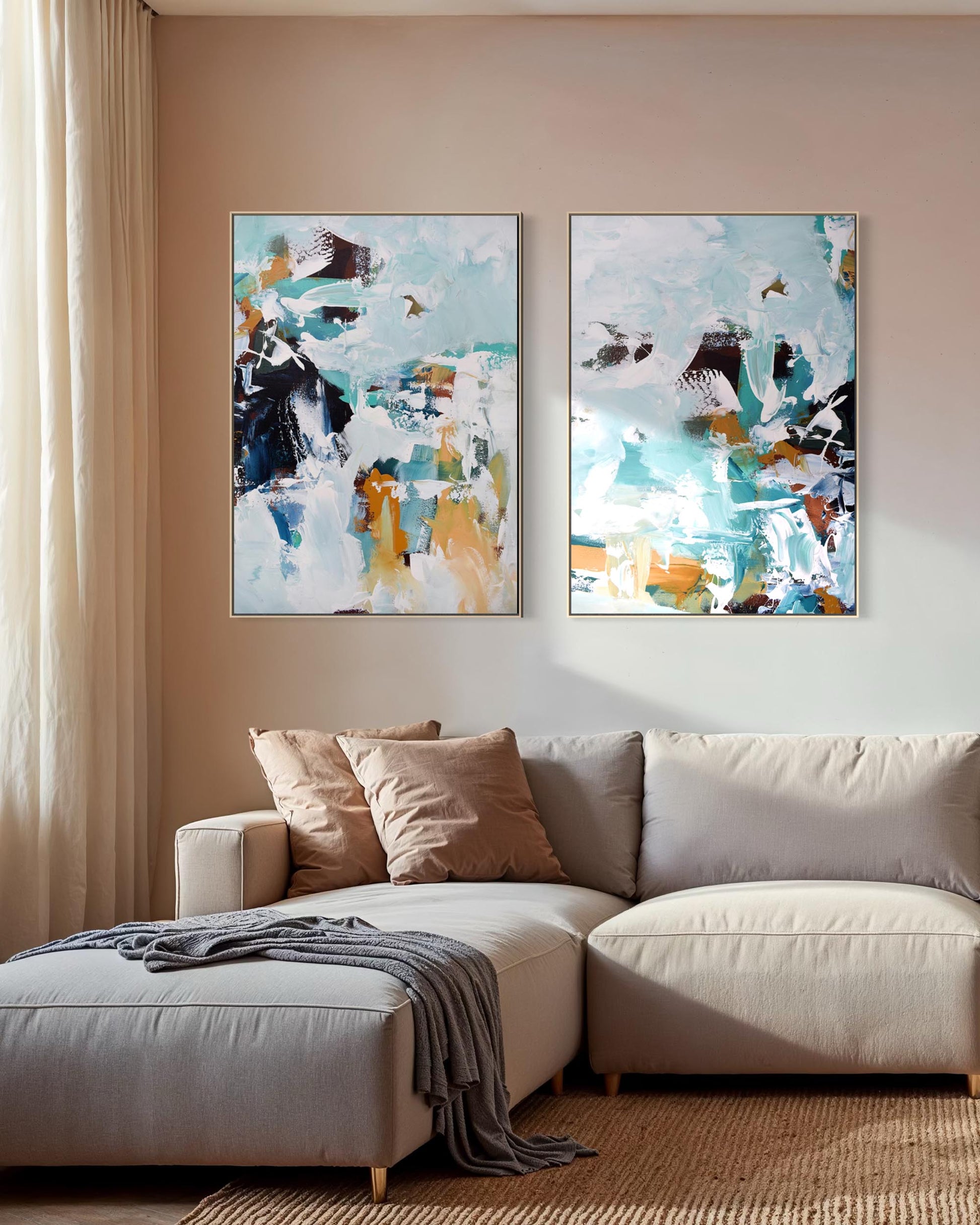 Two abstract paintings on a wall above a beige sofa with decorative pillows.