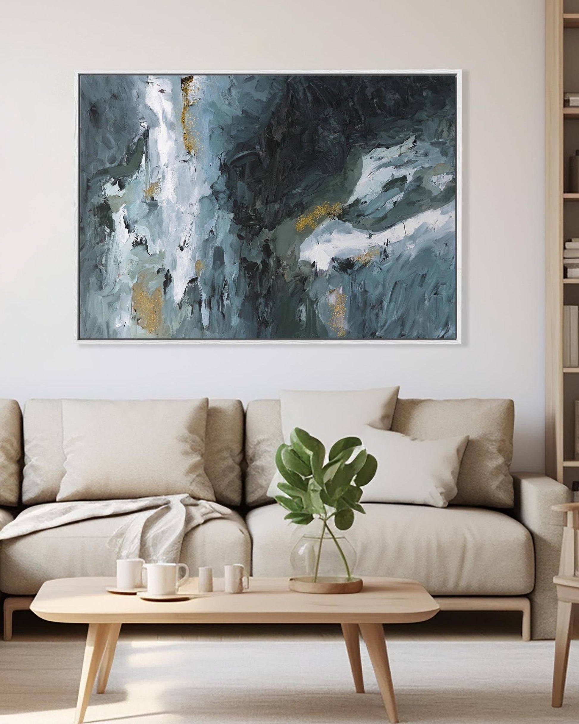 Abstract painting on a wall above a beige sofa in a living room.