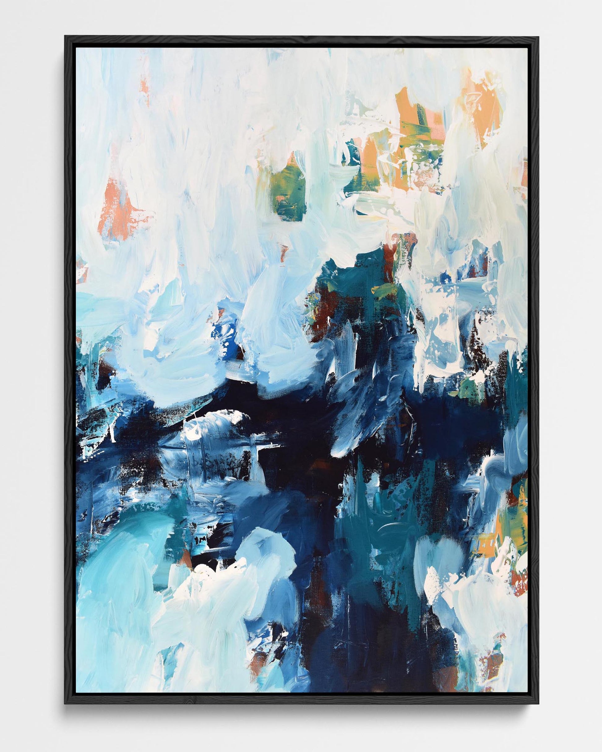 A framed canvas with an abstract design featuring various shades of blue, white, and hints of orange.