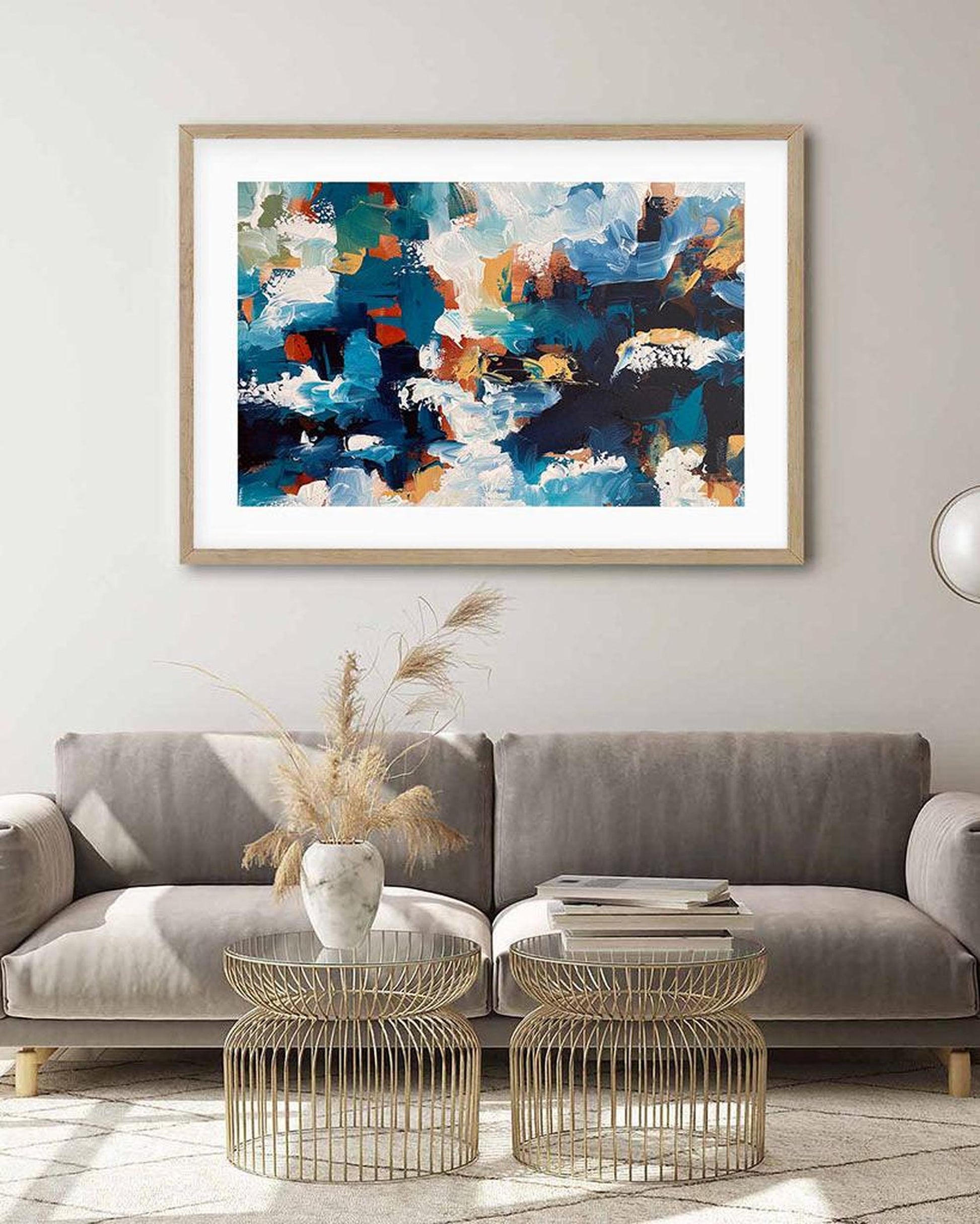 Living room with a gray sofa, wire coffee tables, and a colorful abstract painting on the wall.