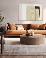 Modern living room with brown sofa, round coffee table, and abstract art on the wall.