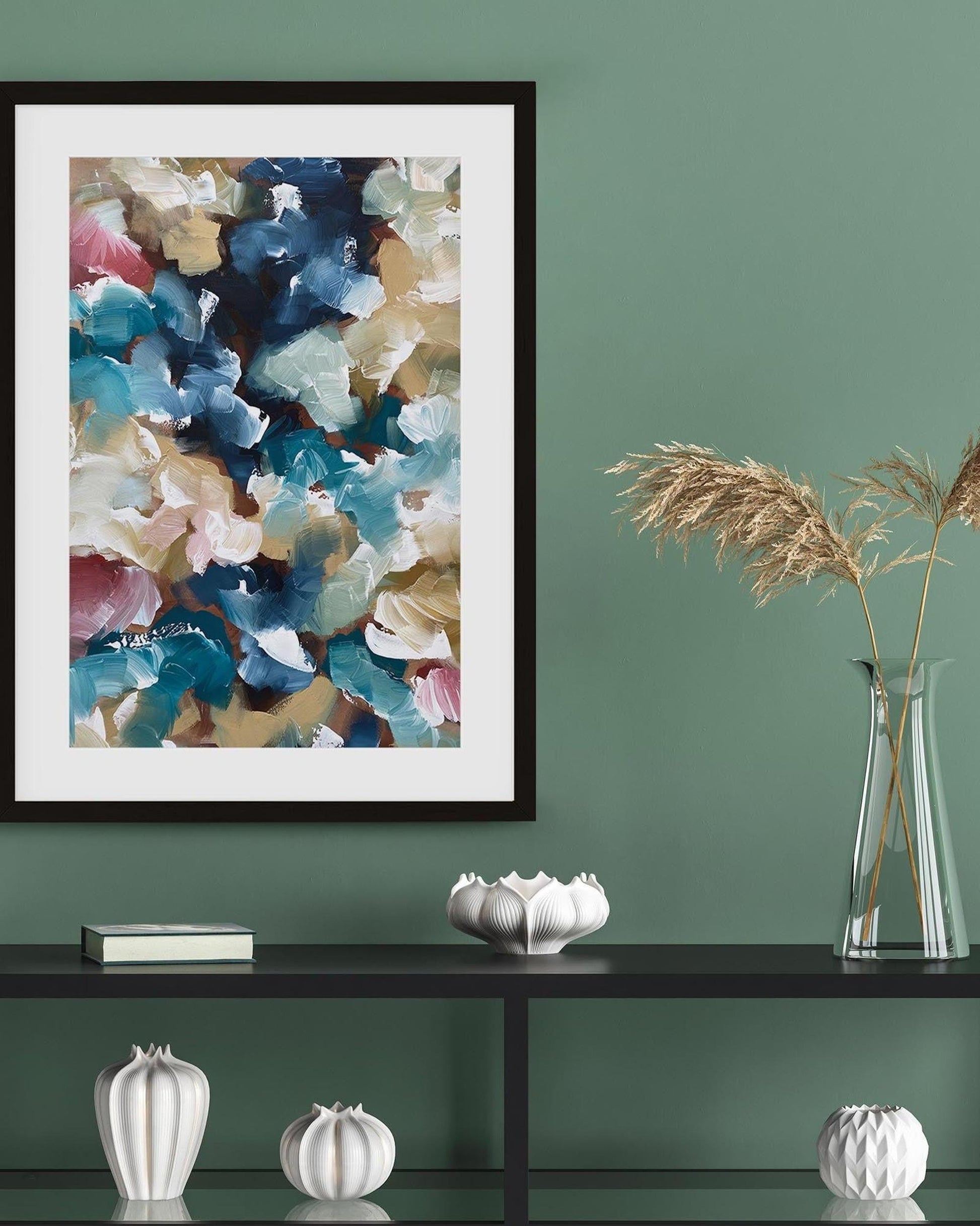 Framed abstract art on a green wall with decorative items below.