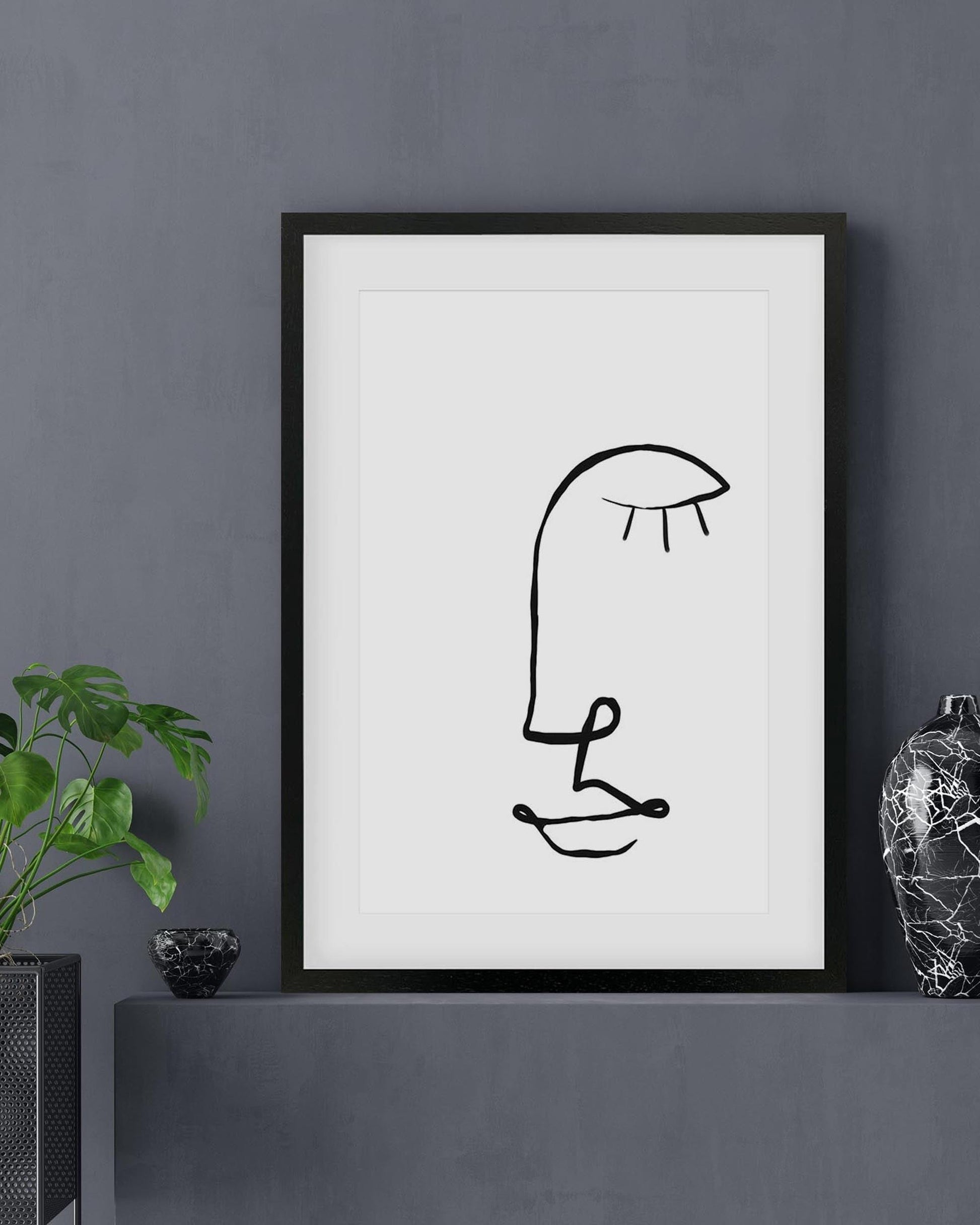 Framed abstract artwork of a person holding an umbrella on a dark gray wall.