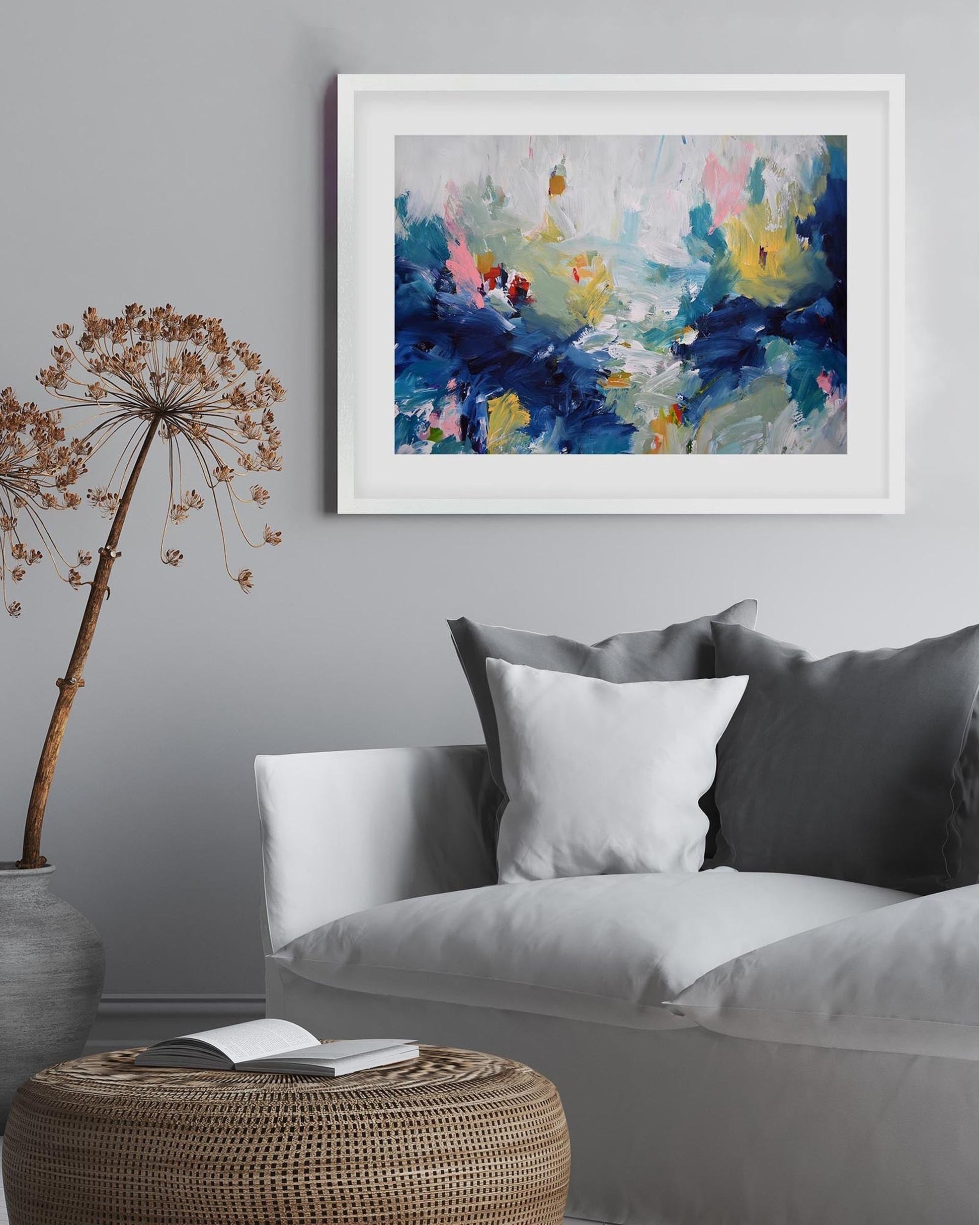Living room with a gray sofa, wicker table, and abstract painting on the wall.
