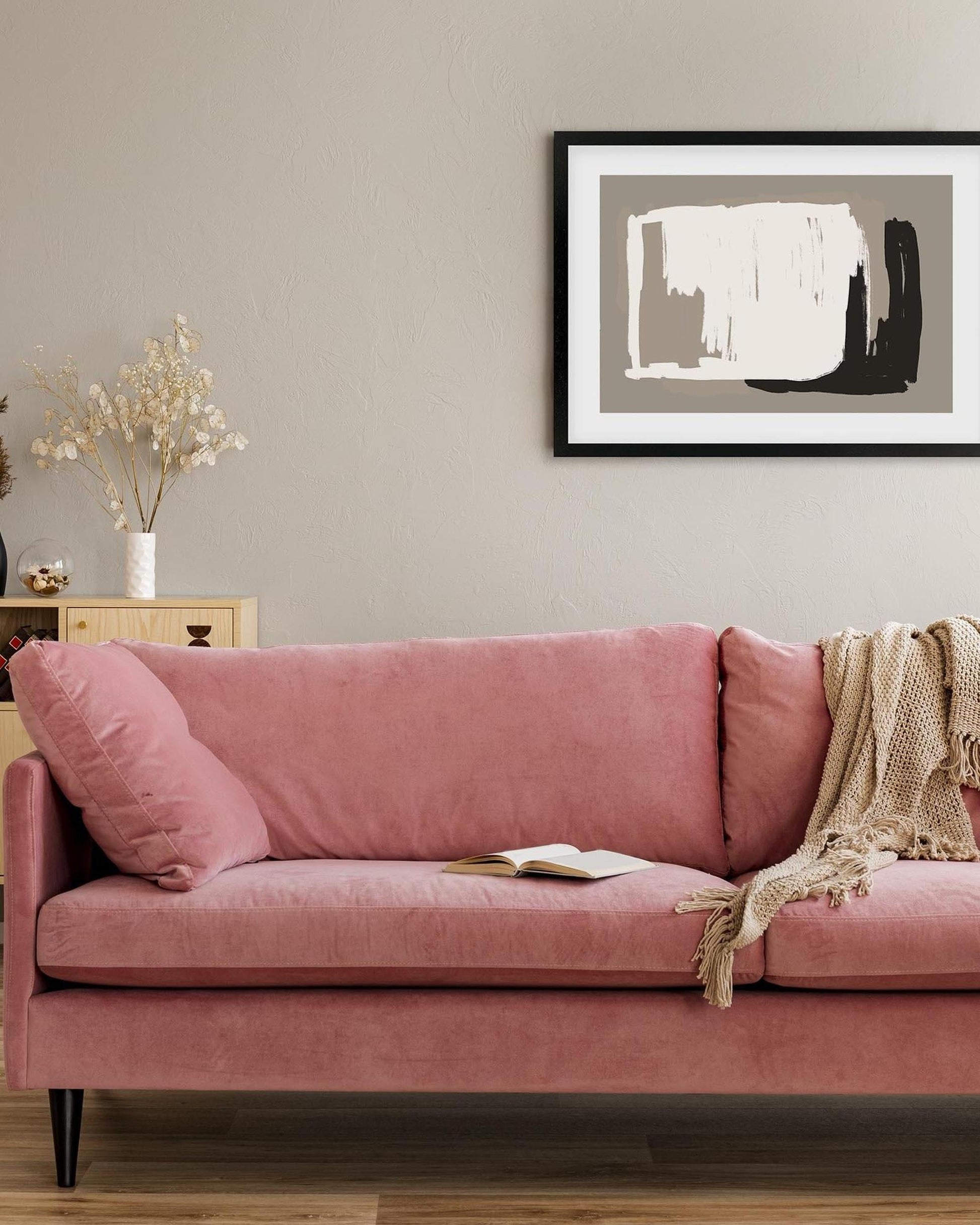 Pink sofa in a living room with a framed abstract art piece on the wall.