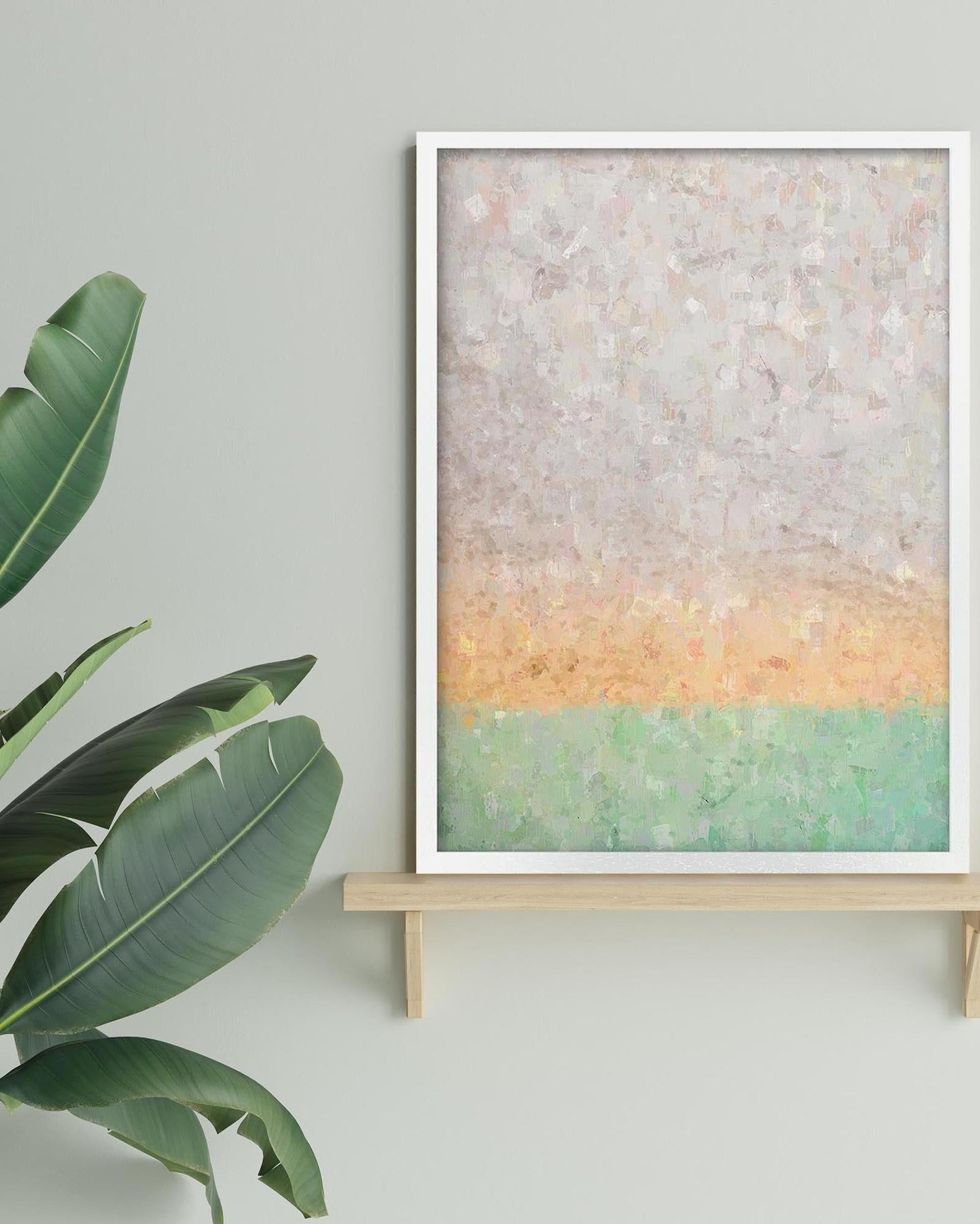 Framed abstract art piece on a light green wall with a plant to the left.