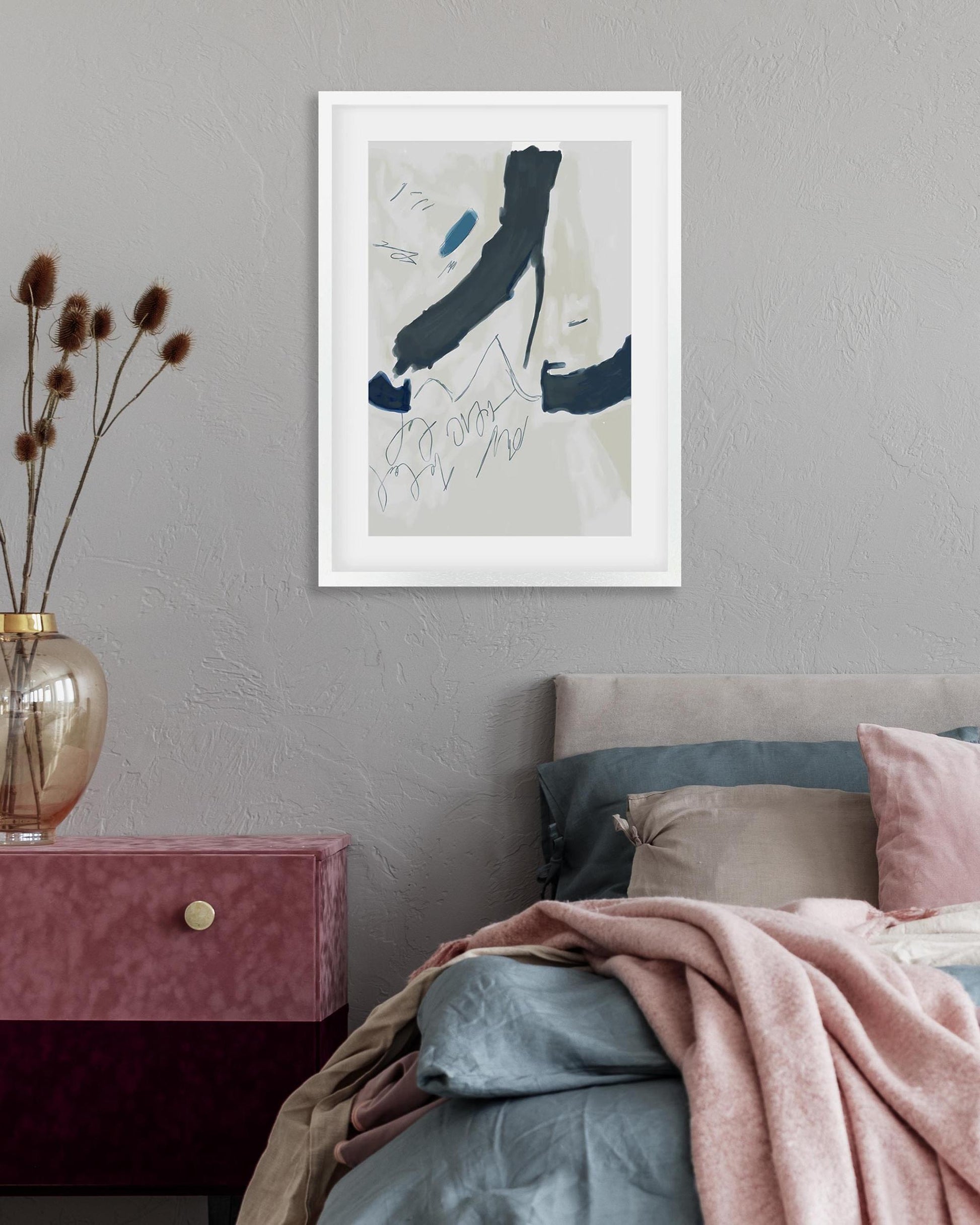 Framed abstract art above a bed with pink and gray bedding.