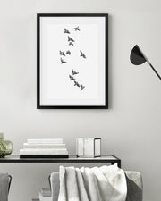 Framed black and white artwork of birds on a wall above a console table.