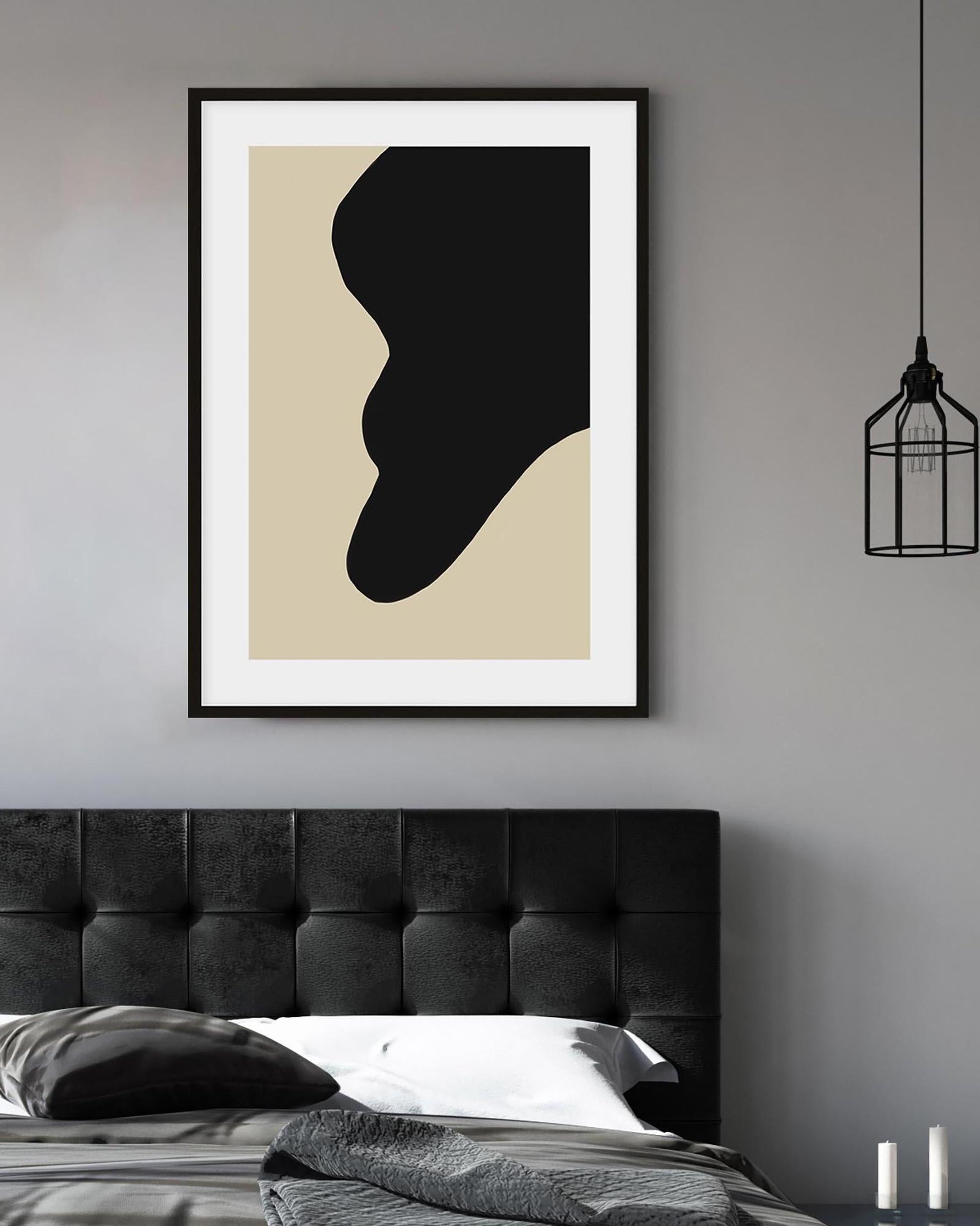 Framed abstract art print on a wall above a bed with a dark headboard.