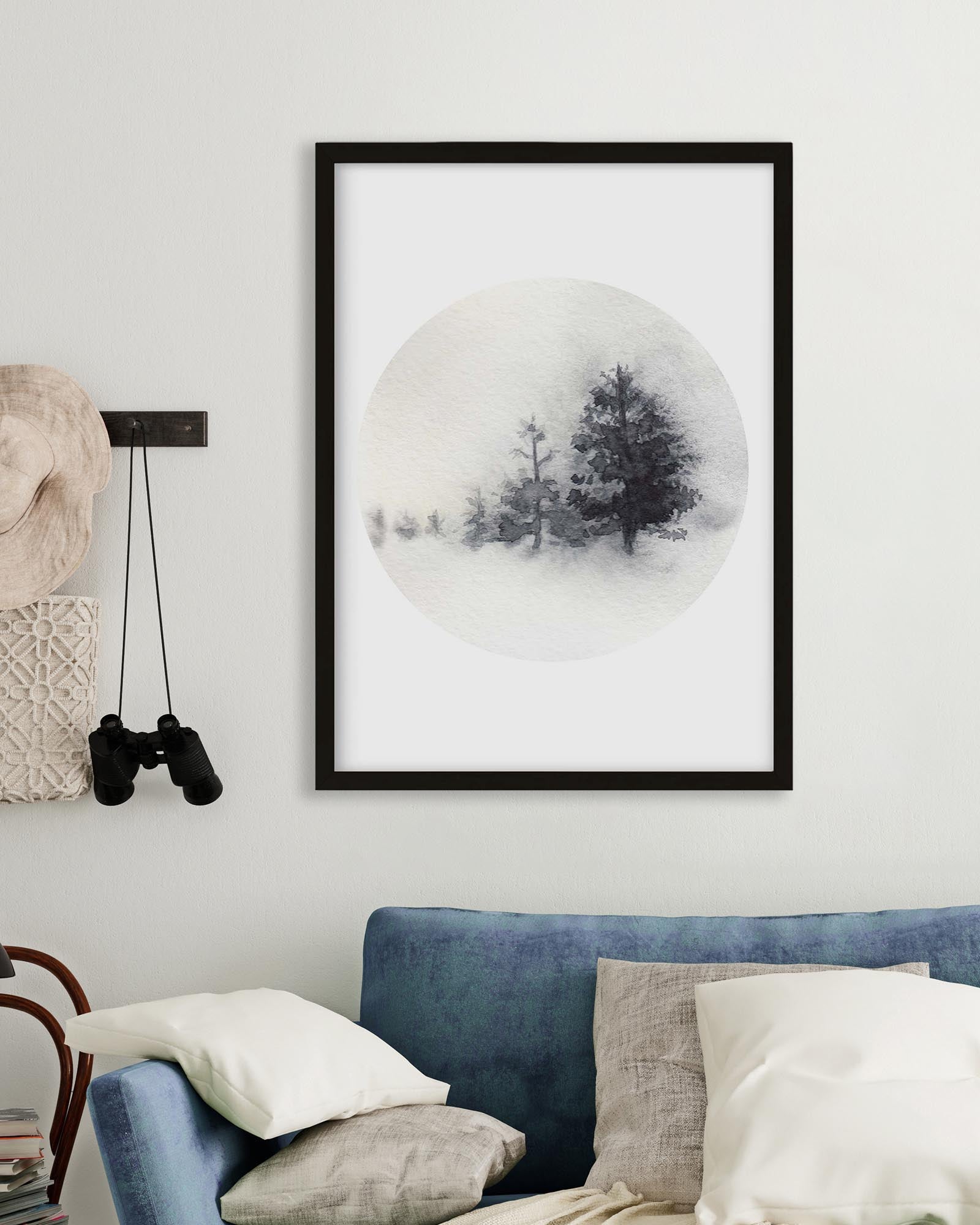 Framed artwork of trees in a snowy landscape on a wall above a sofa.