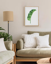 Living room with a green leaf print on the wall, beige sofa, and armchair.