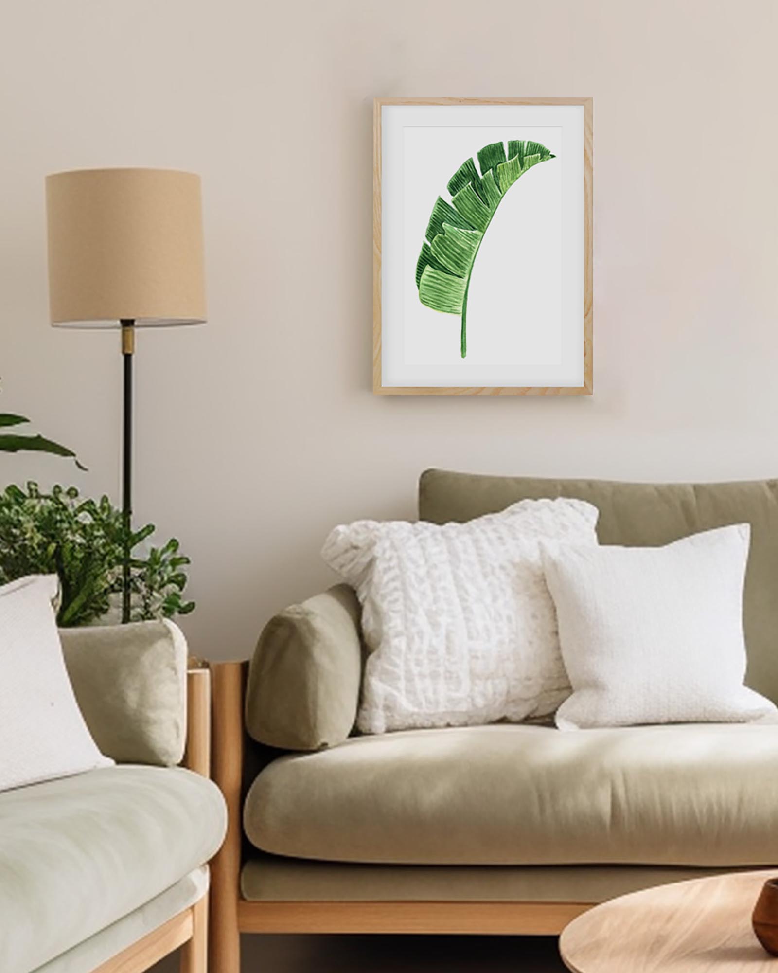 Living room with a green leaf print on the wall, beige sofa, and armchair.