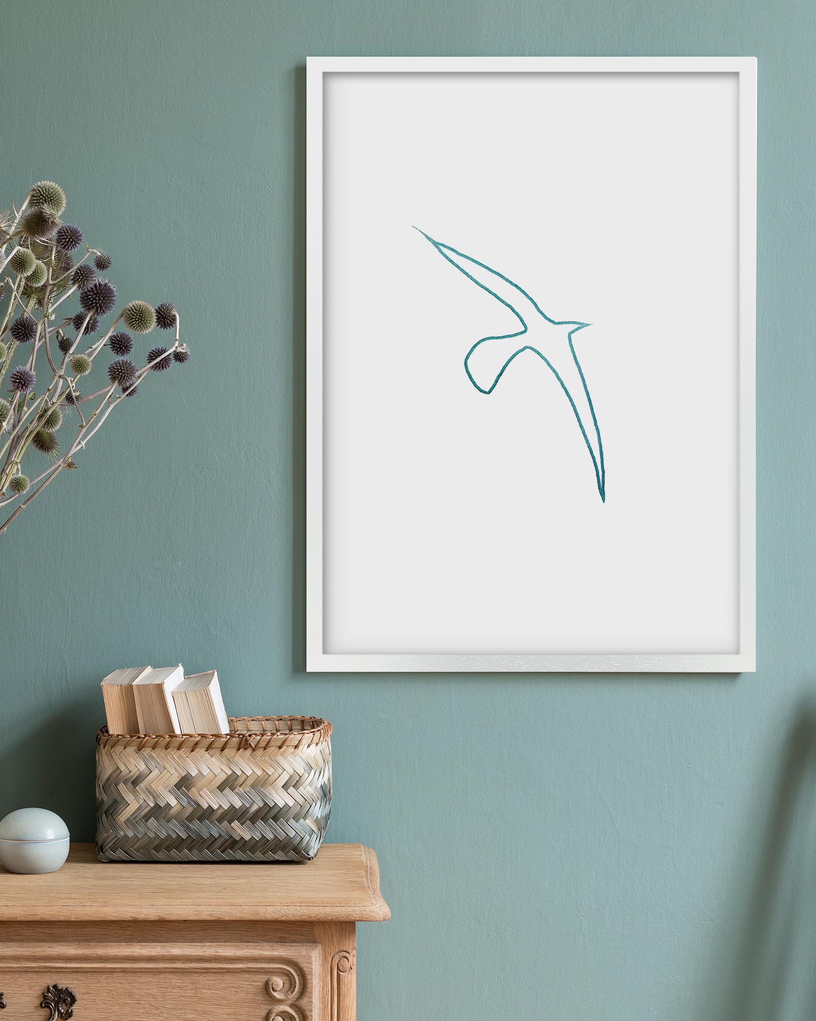 Framed abstract artwork on a wall with a wooden cabinet and basket below.