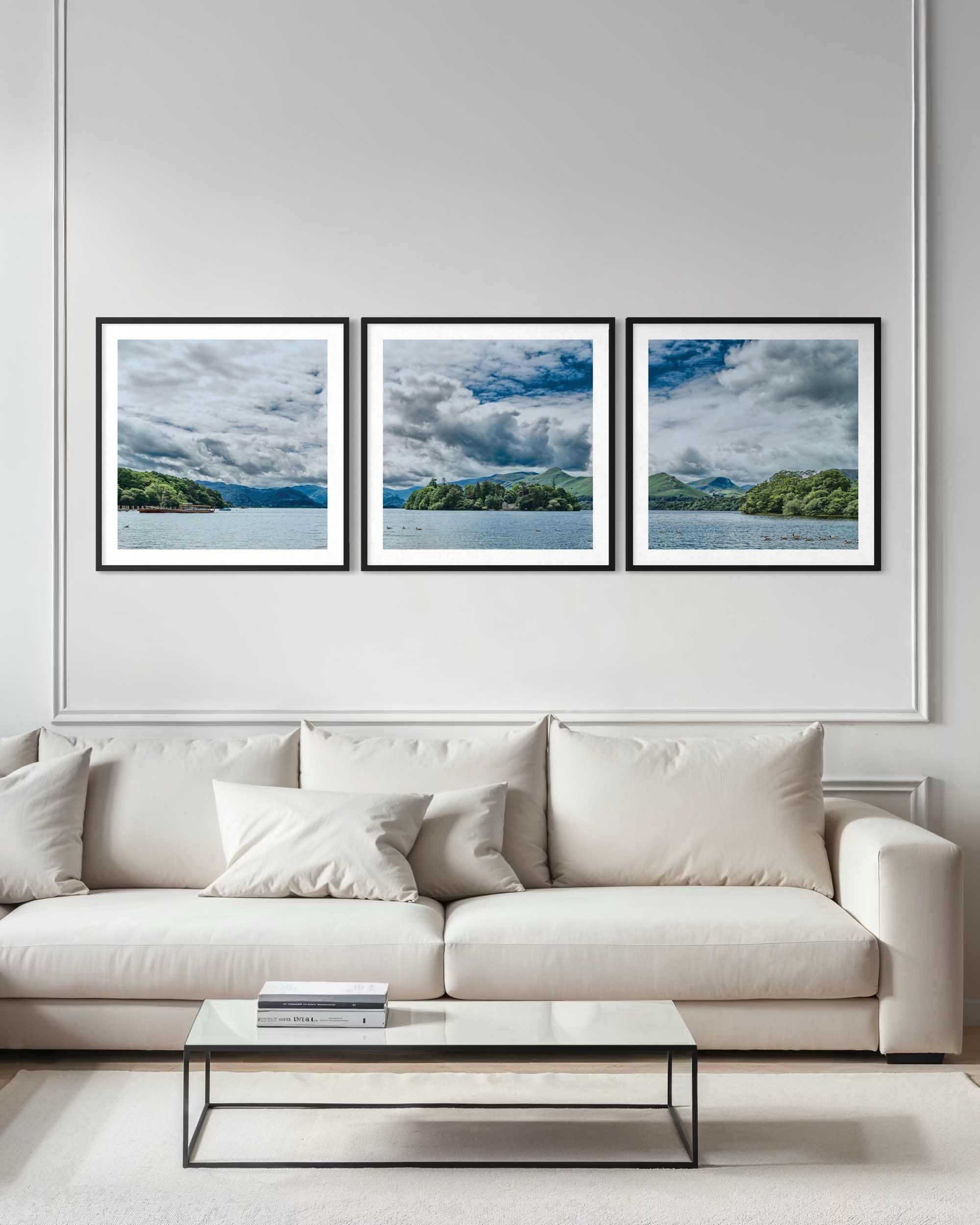 Three framed landscape pictures above a white sofa in a living room.