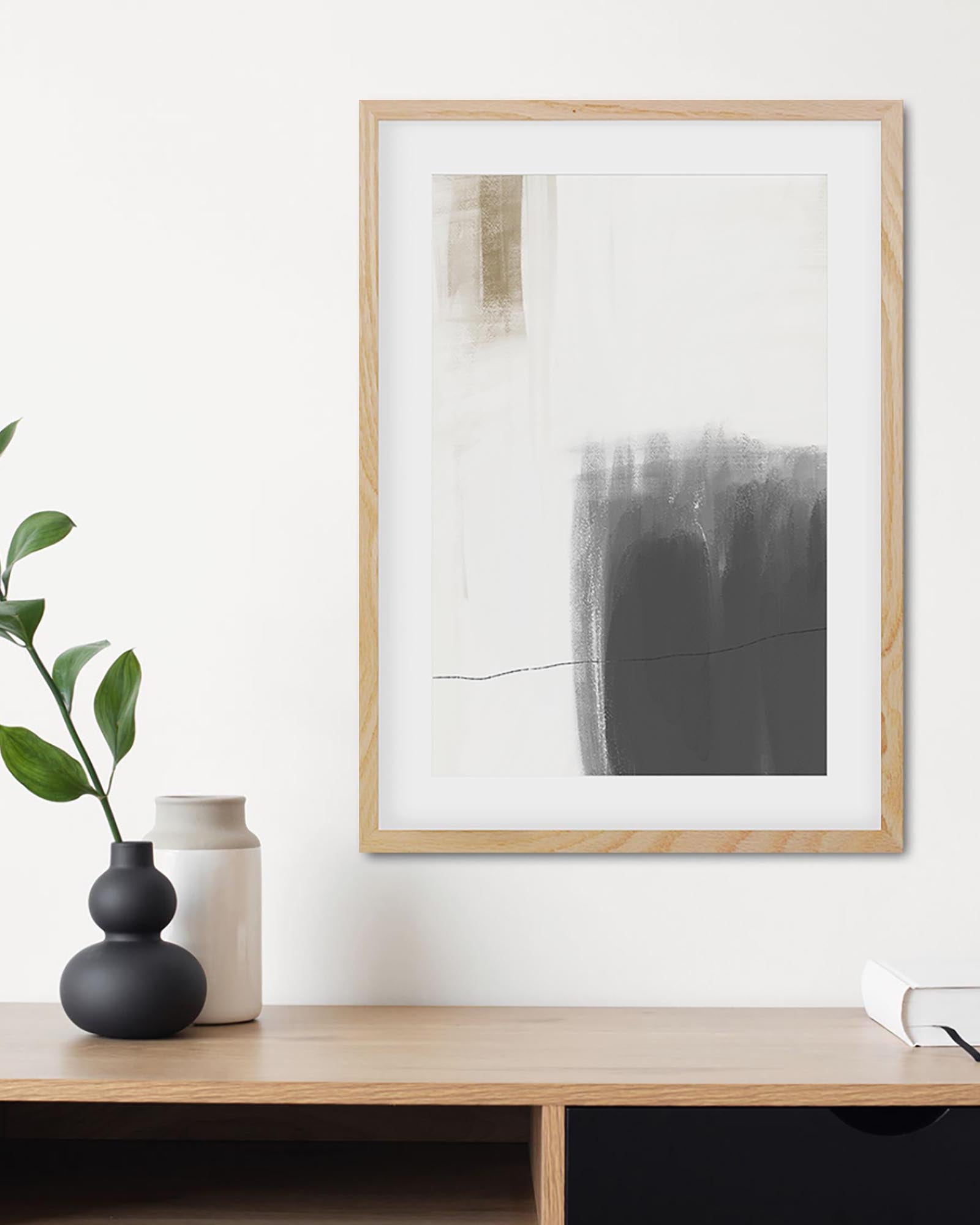 Framed abstract art piece on a wall above a wooden shelf with decorative vases and a plant.