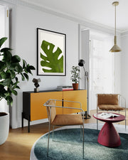 Modern living room with yellow cabinet, brown chairs, and a green leafy plant.