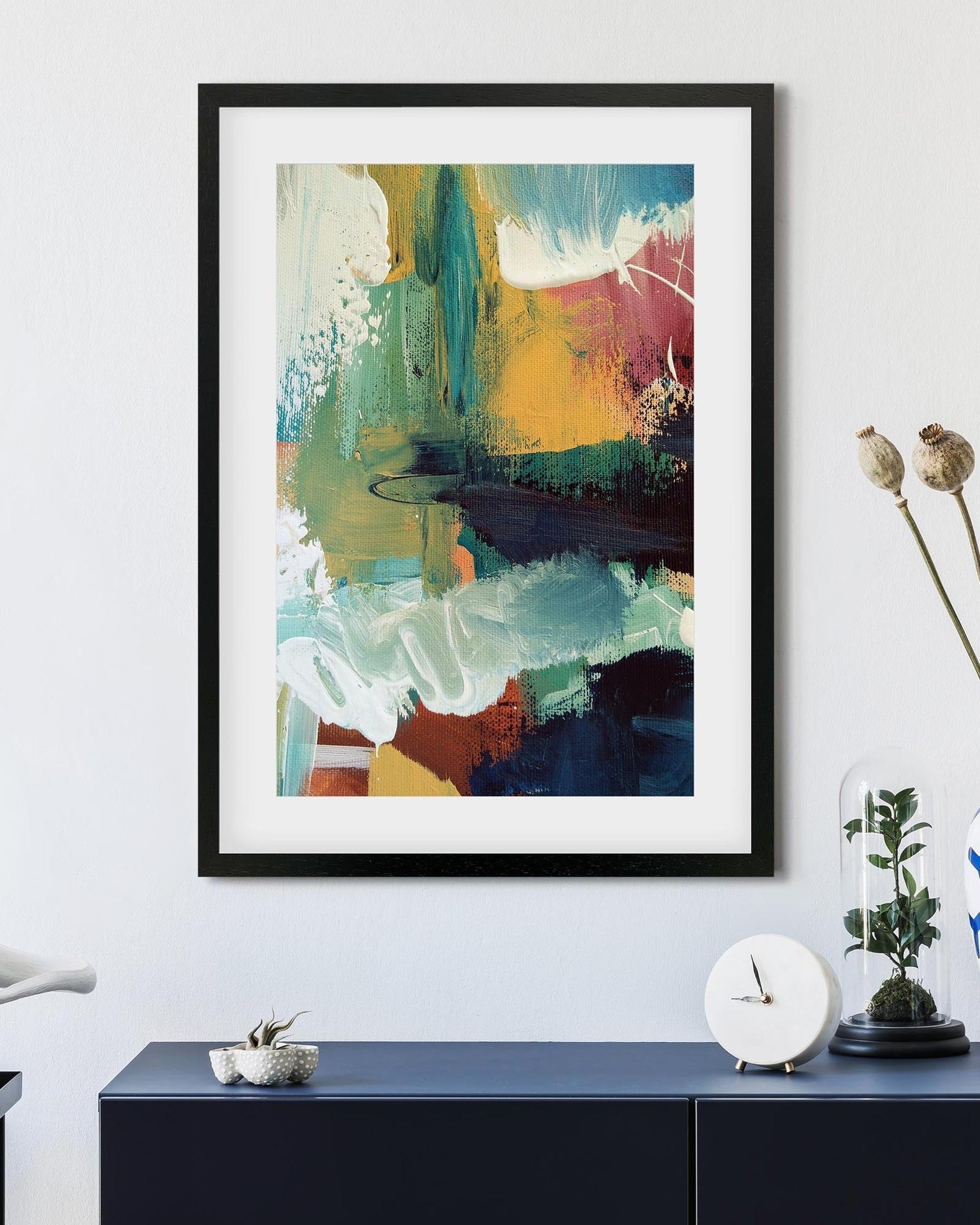 Framed abstract art piece on a wall above a console table with decorative items.