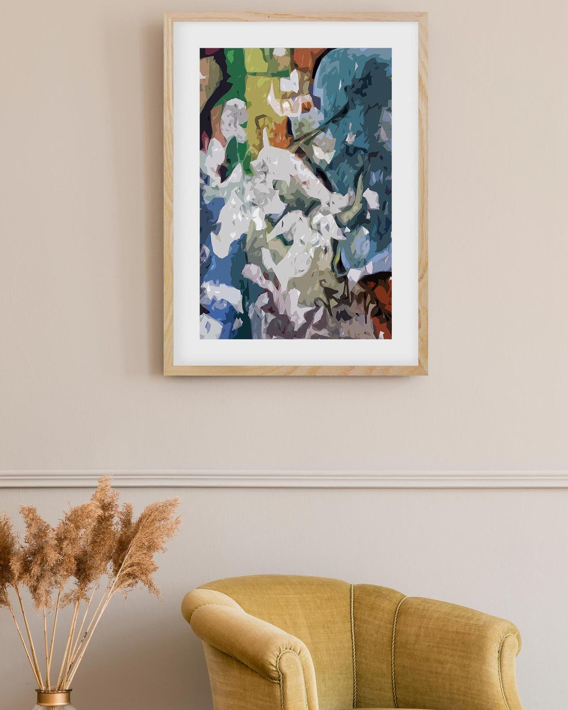 Framed abstract artwork on a wall above a yellow armchair with decorative elements.