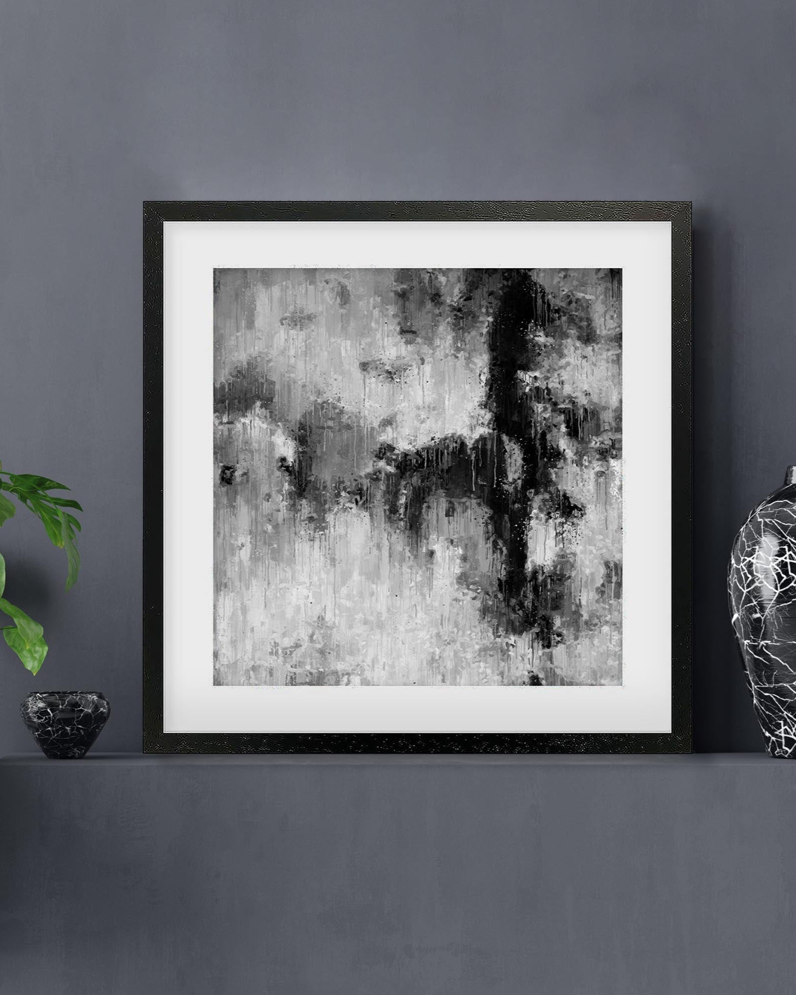 Framed abstract art print on a gray wall with decorative items.